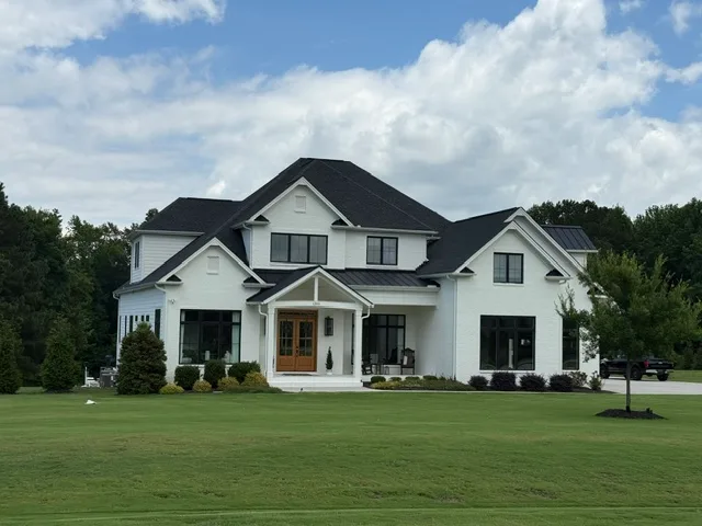 Modern farmhouse exterior with crisp white siding and dark metal roofing accents