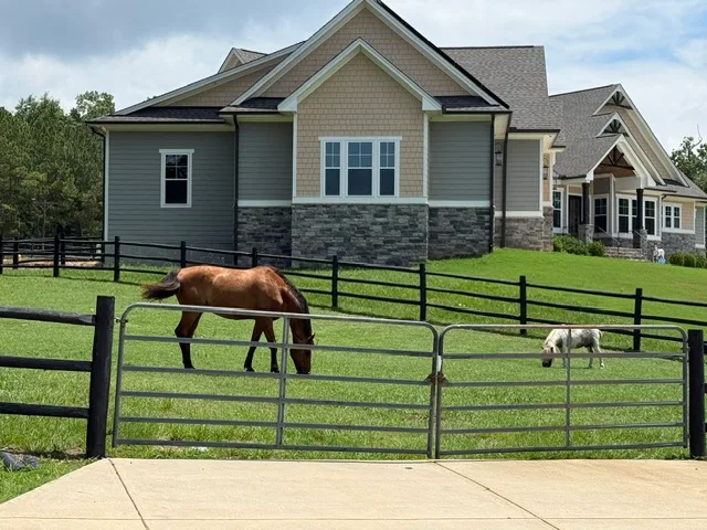 Side profile of the home showing Craftsman-inspired architecture with fenced pasture