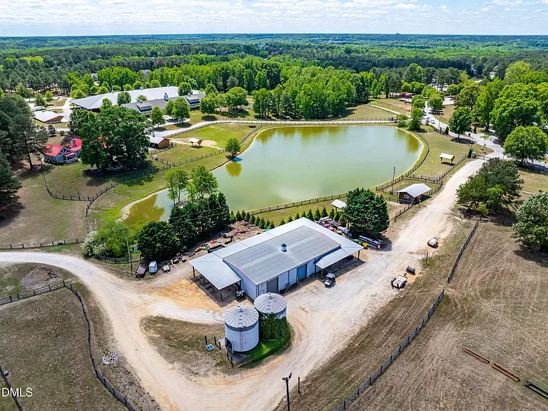 Aerial drone shot of large rural equestrian property with barn, silos, and fenced paddocks