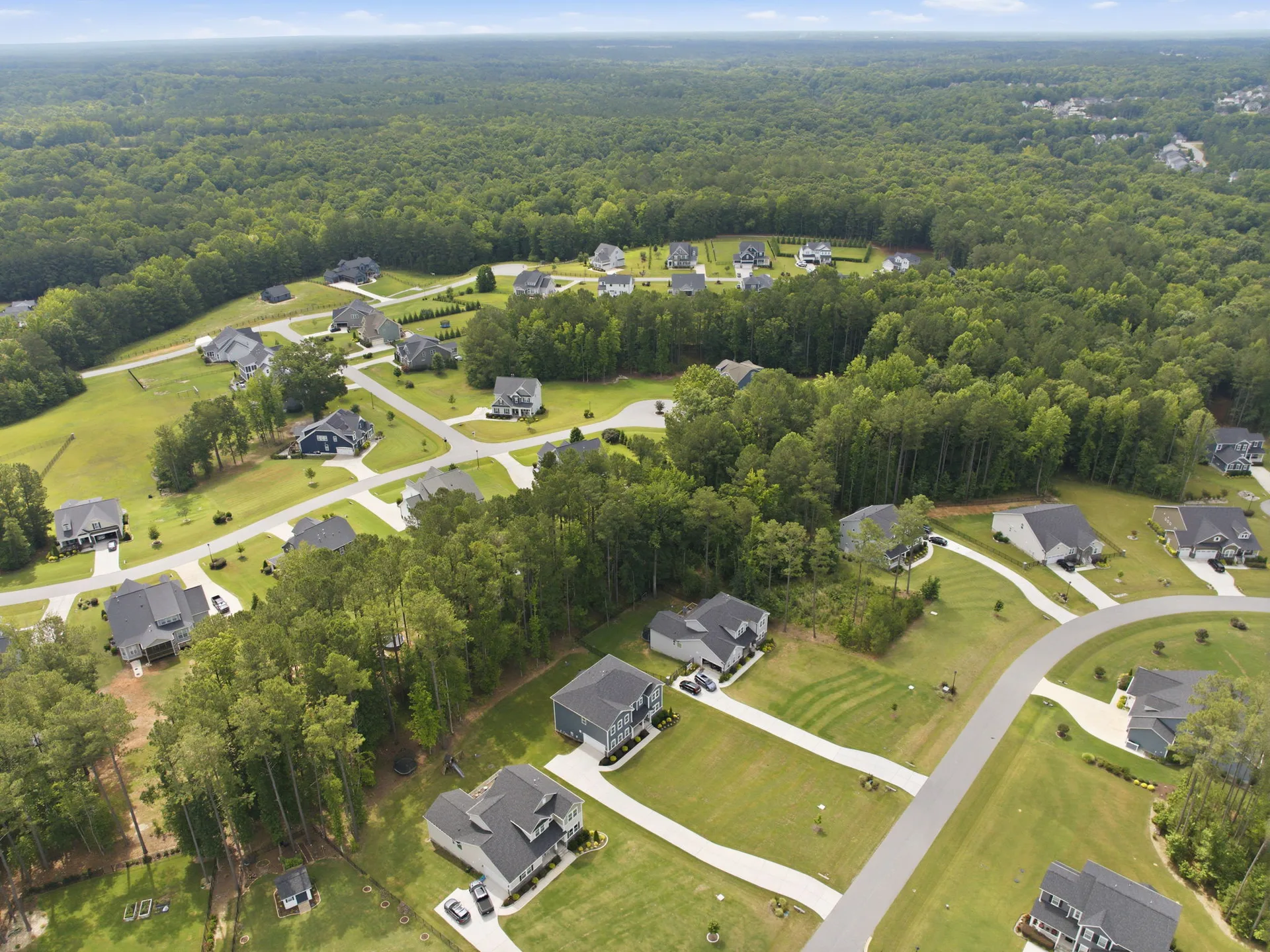 Drone shot of residential neighborhood nestled in a wooded landscape with multiple homes