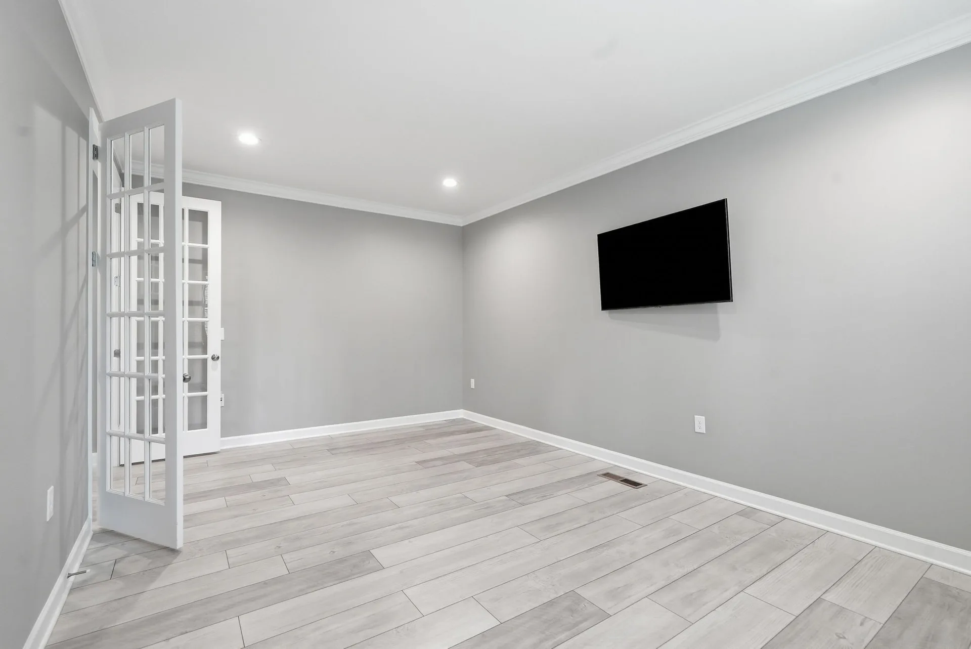 Wide-angle view of the home office with recessed lighting, LVP flooring, and white French doors