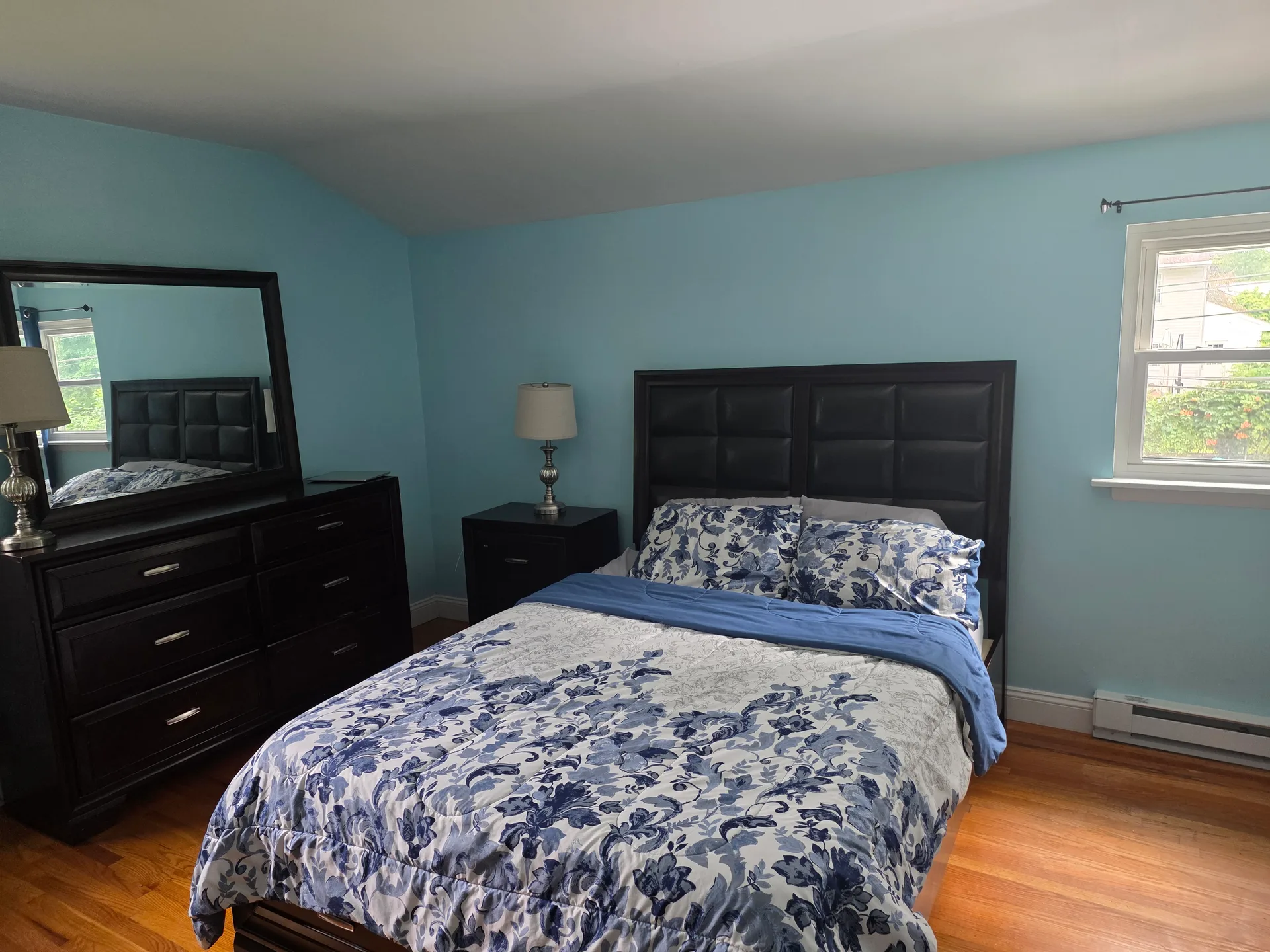 Master bedroom with light blue walls and hardwood flooring