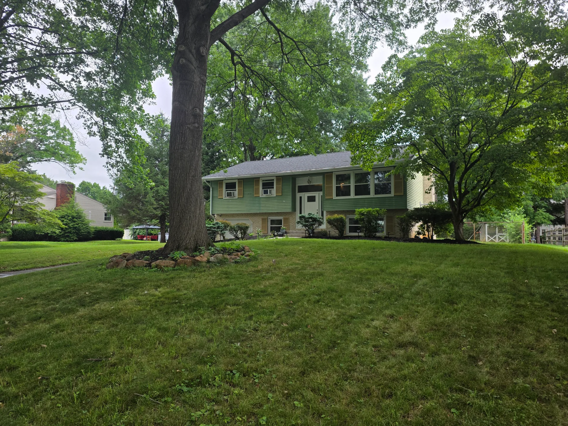Front lawn view of the bi-level home with mature trees
