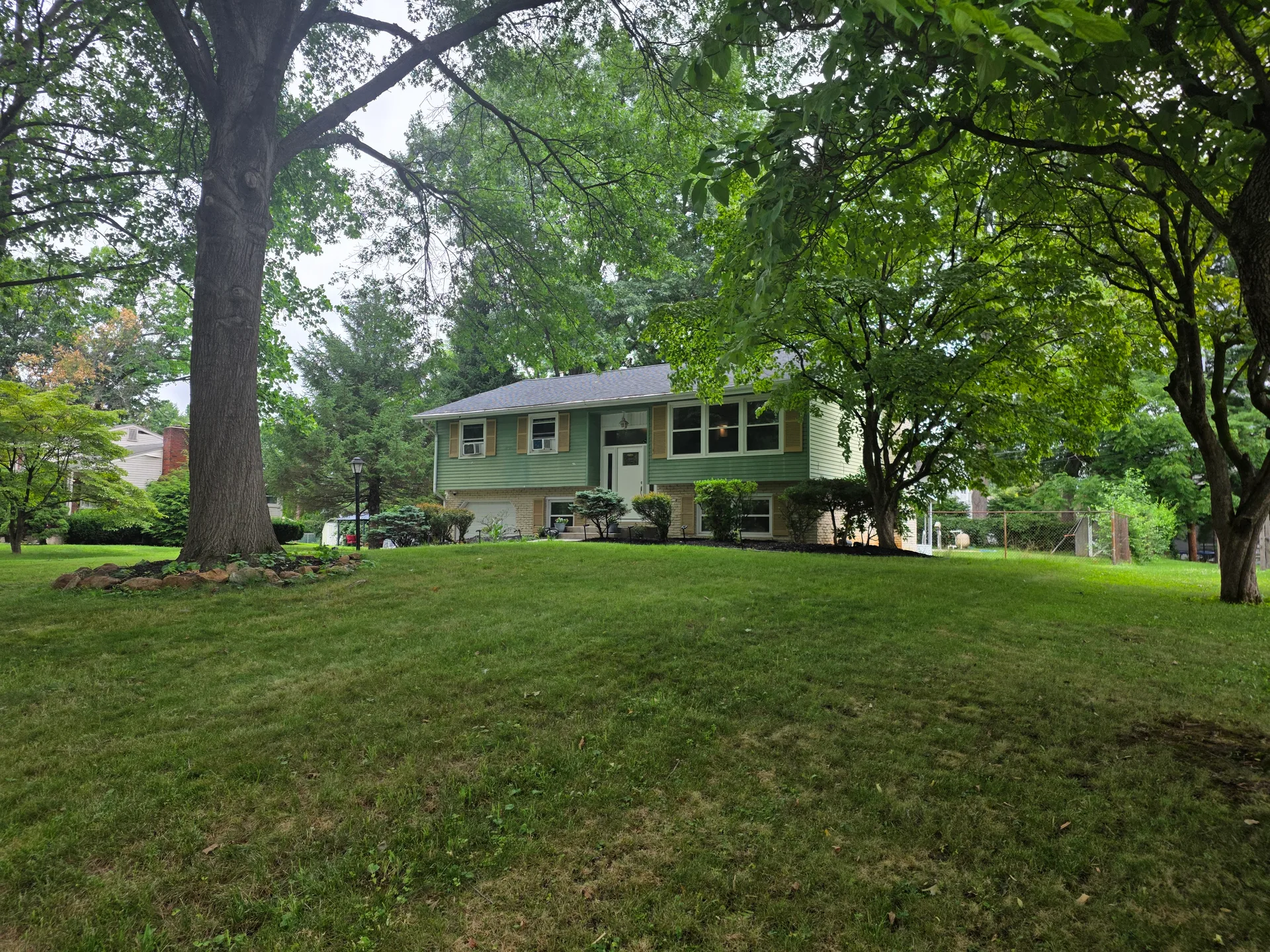 Street view showing green siding and stone lower level
