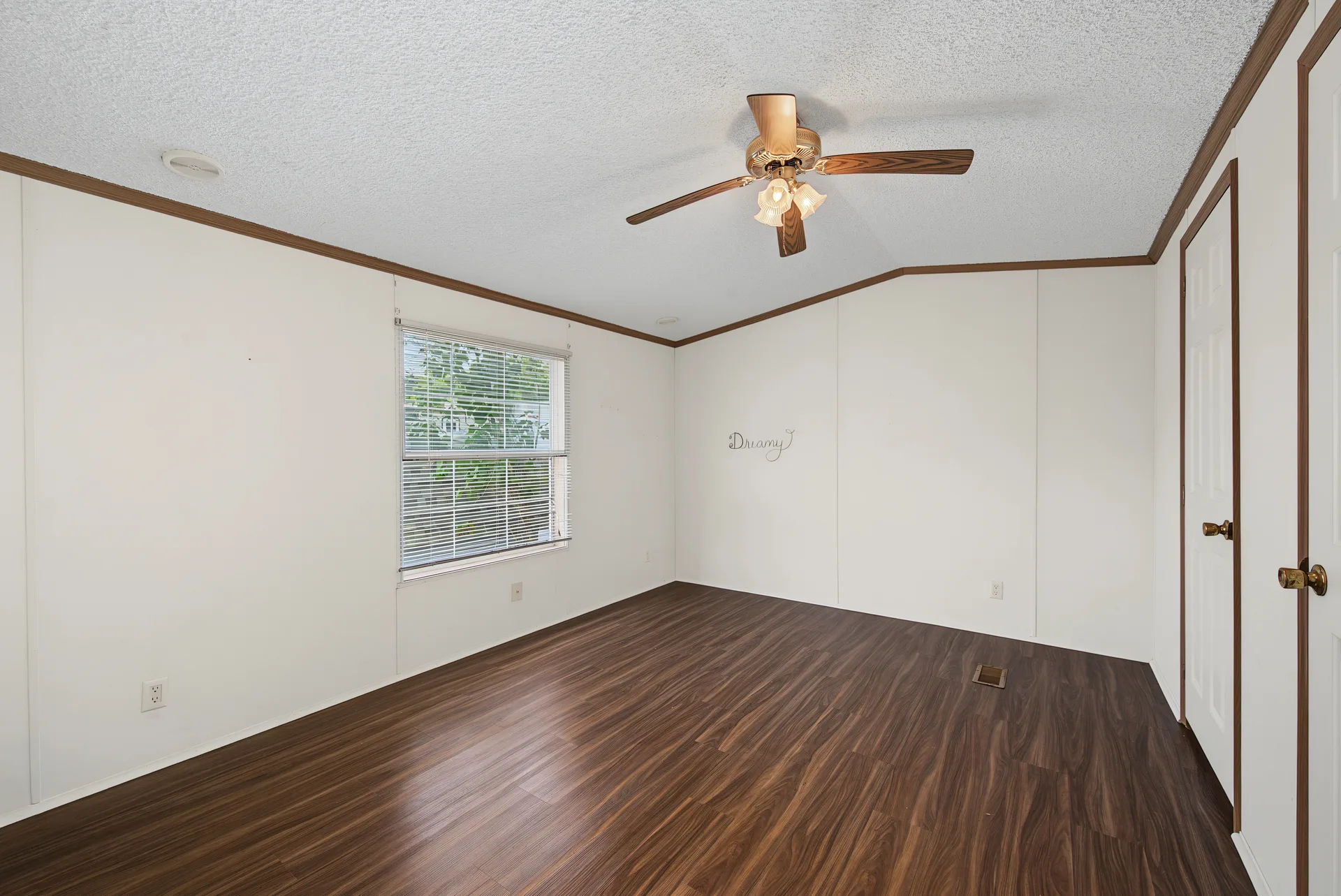 Bedroom interior with white wall paneling, dark wood-look flooring, and ceiling fan