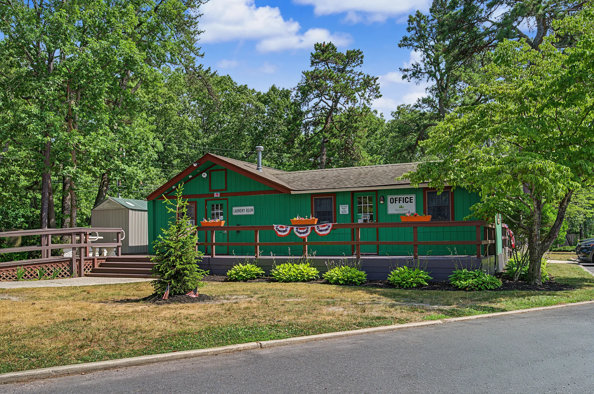 Shady Pines community management office with green siding and patriotic bunting