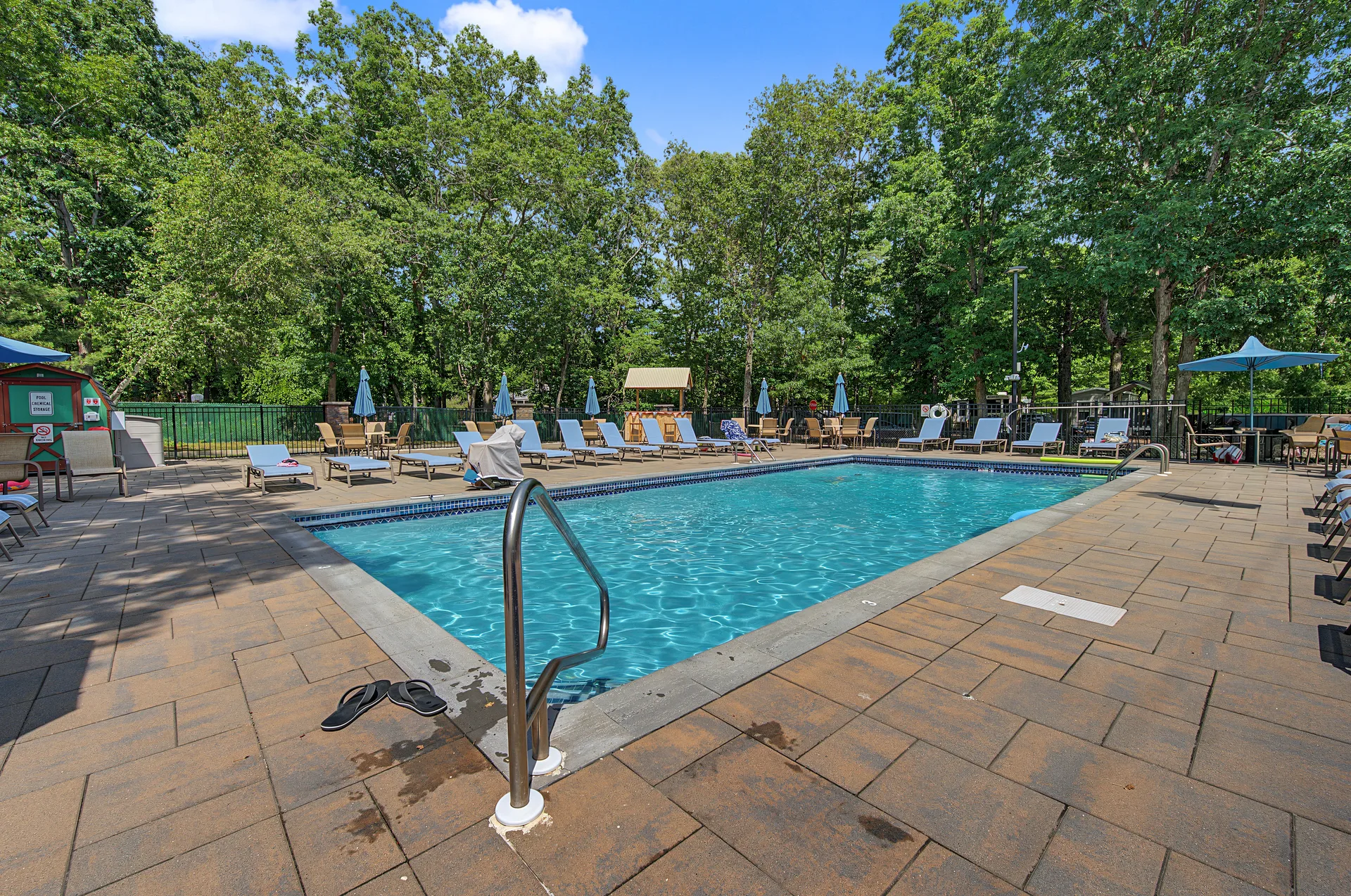 Outdoor community pool with concrete paver decking and metal railings