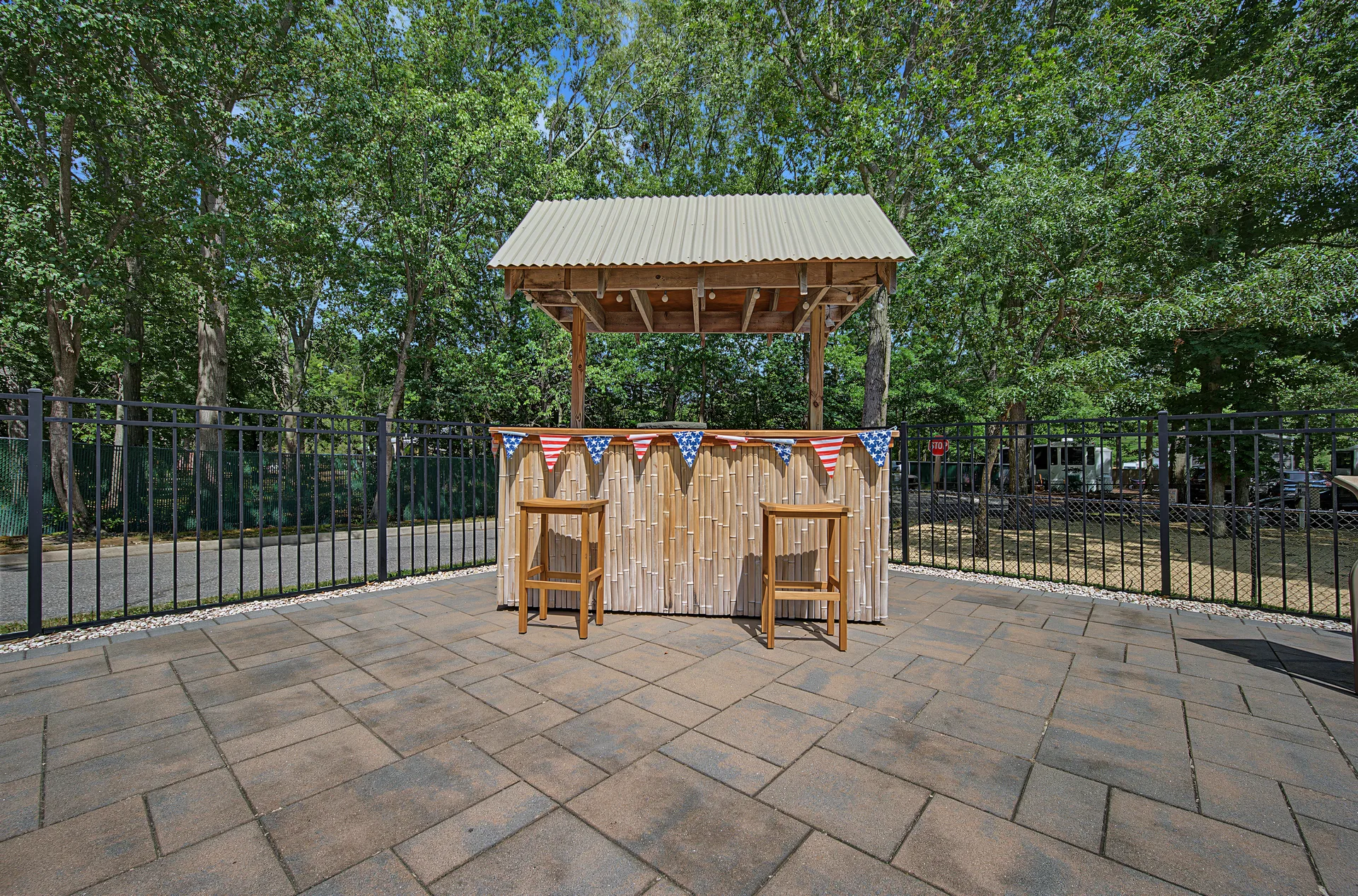 Community tiki bar with bamboo siding, corrugated metal roof, and patriotic bunting