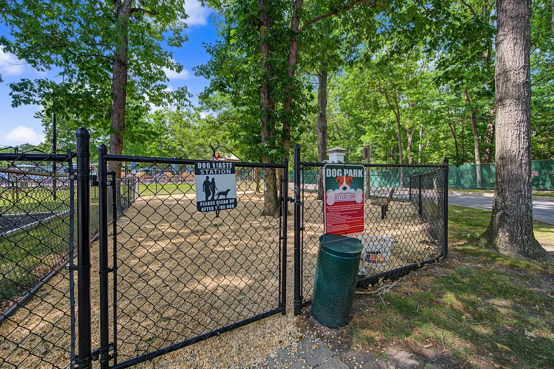 Fenced community dog park with wood chip ground cover and shade trees