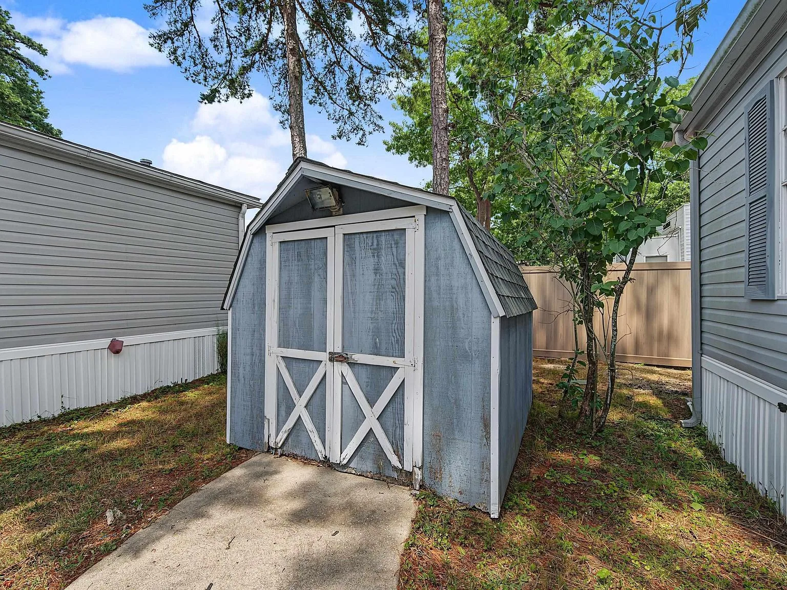 Standalone wooden storage shed with blue siding in the side yard