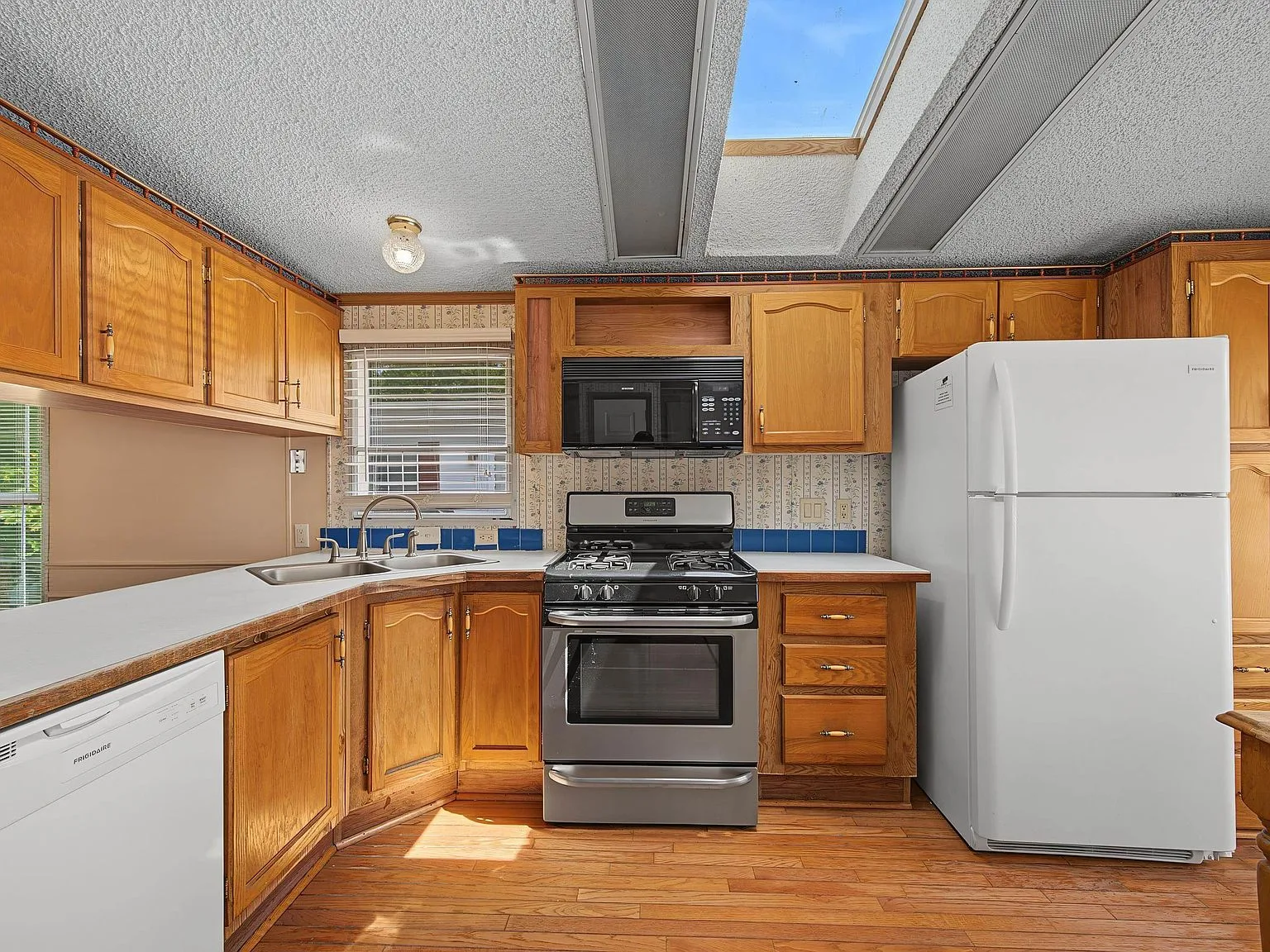Kitchen with honey oak cabinetry, laminate countertops, and skylight