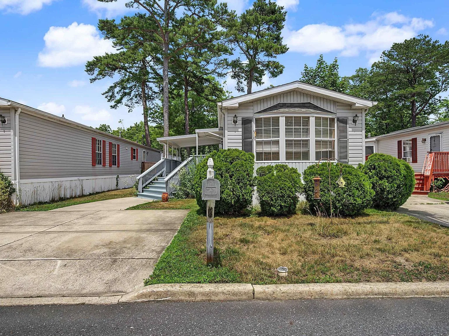 Manufactured home with grey vinyl siding, bay window, and large front deck