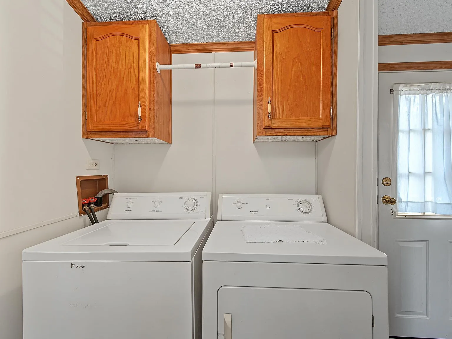 Laundry utility area with side-by-side washer and dryer, upper cabinetry