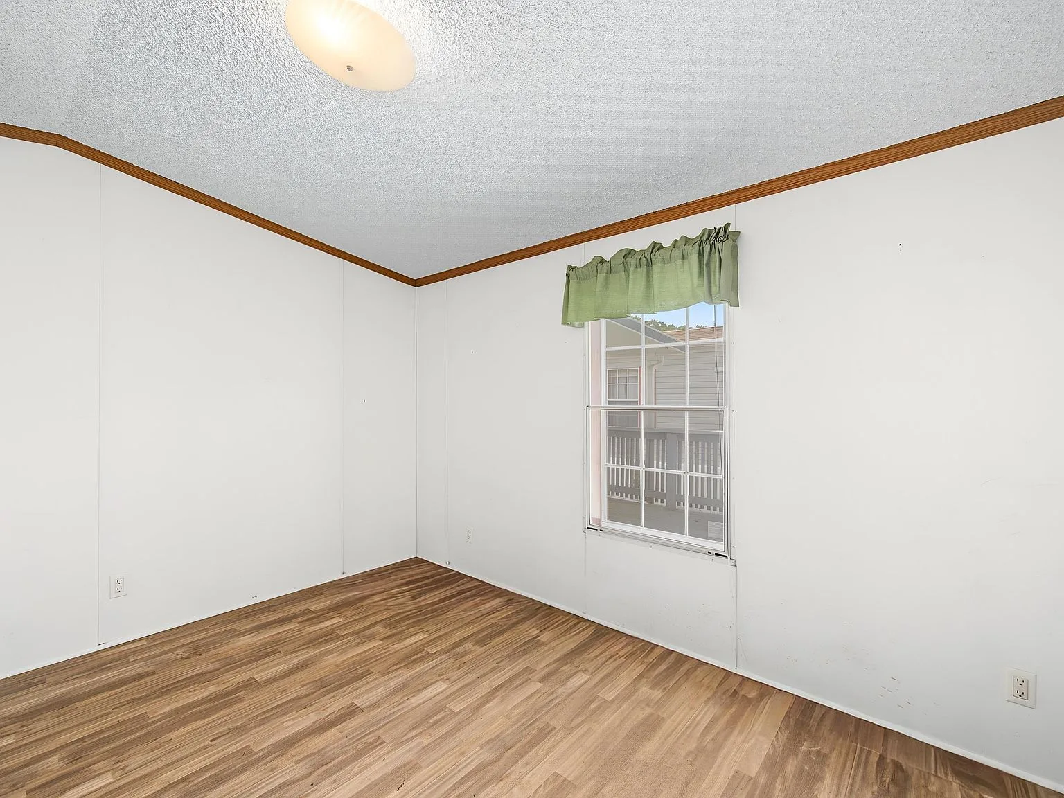 Bedroom interior view with laminate flooring and natural daylight