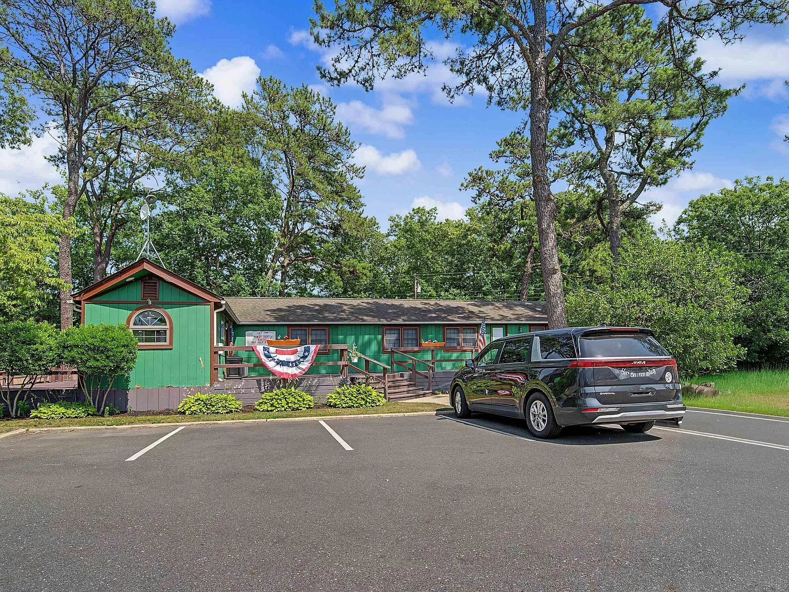 Manufactured home facade with green siding and wooden front deck