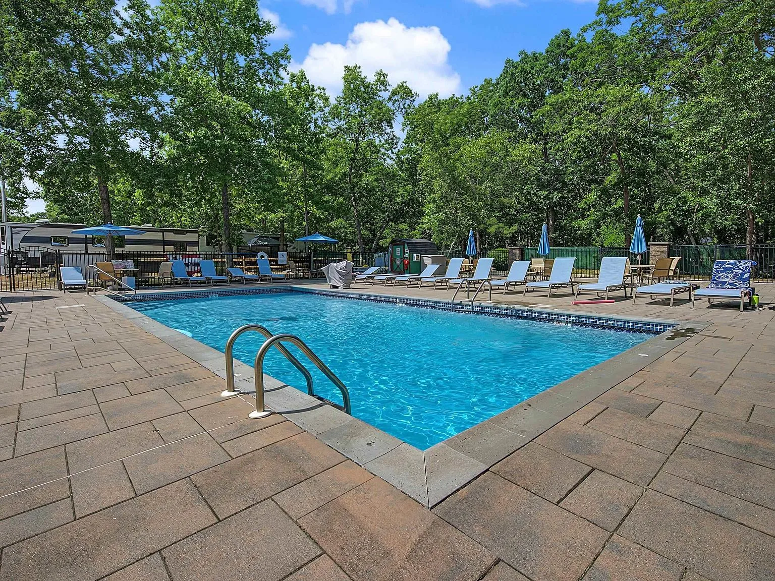 Community pool with lounge chairs and blue patio umbrellas