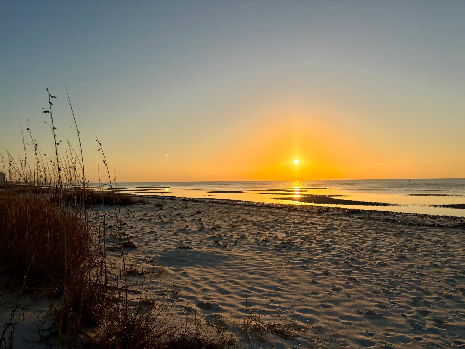 Golden sunrise reflecting on the beach and sand dunes along the Mississippi Gulf Coast