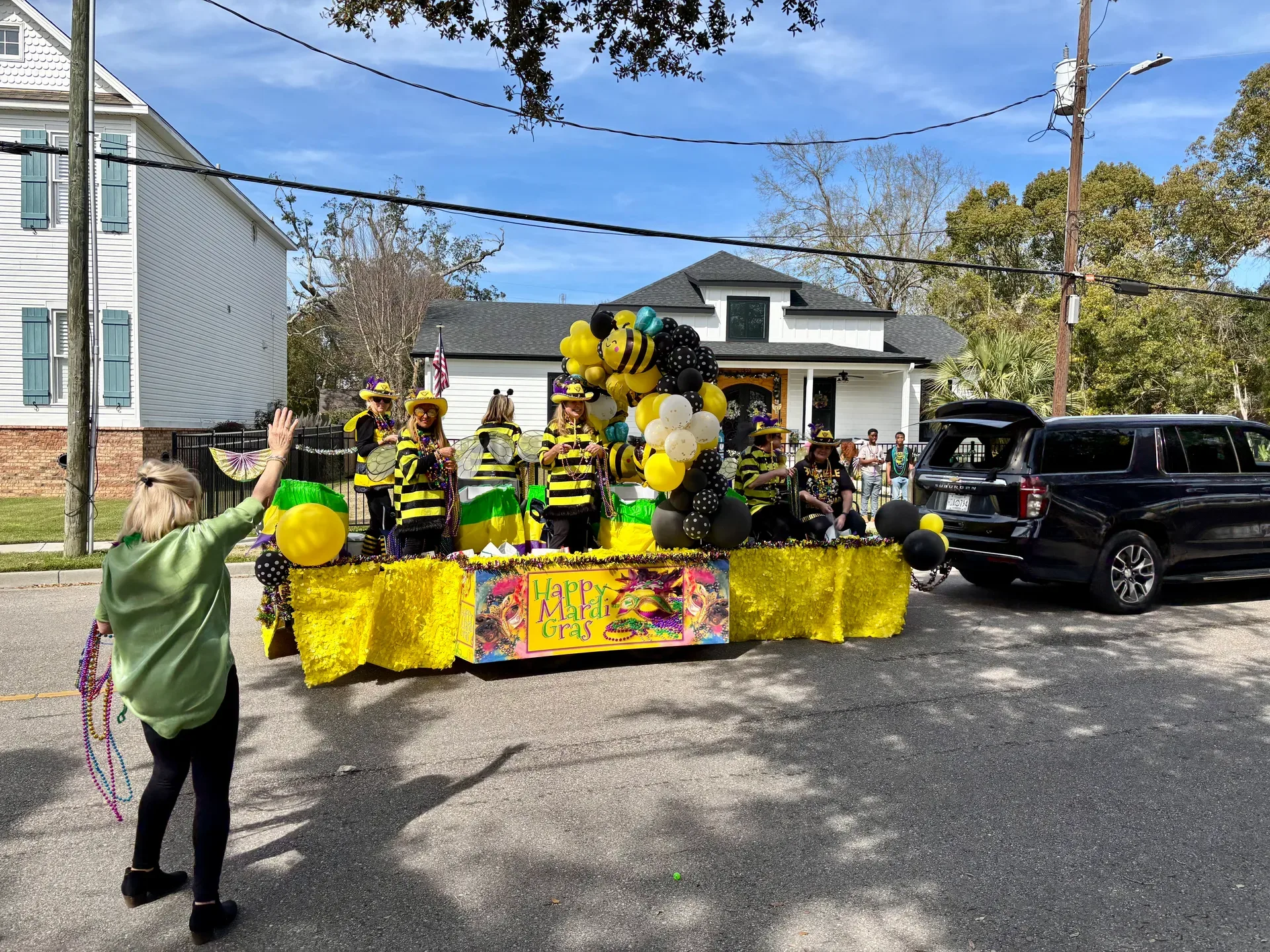 A group of people dressed as bumblebees riding on a brightly decorated Mardi Gras parade float