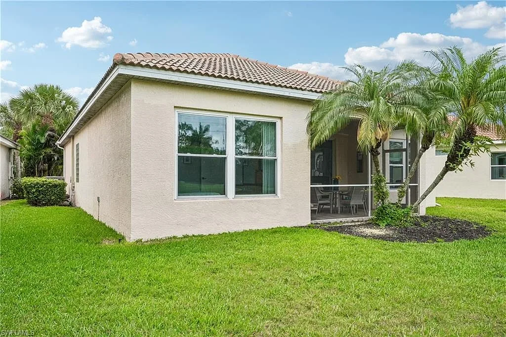Back of the home with screened patio and landscaped yard