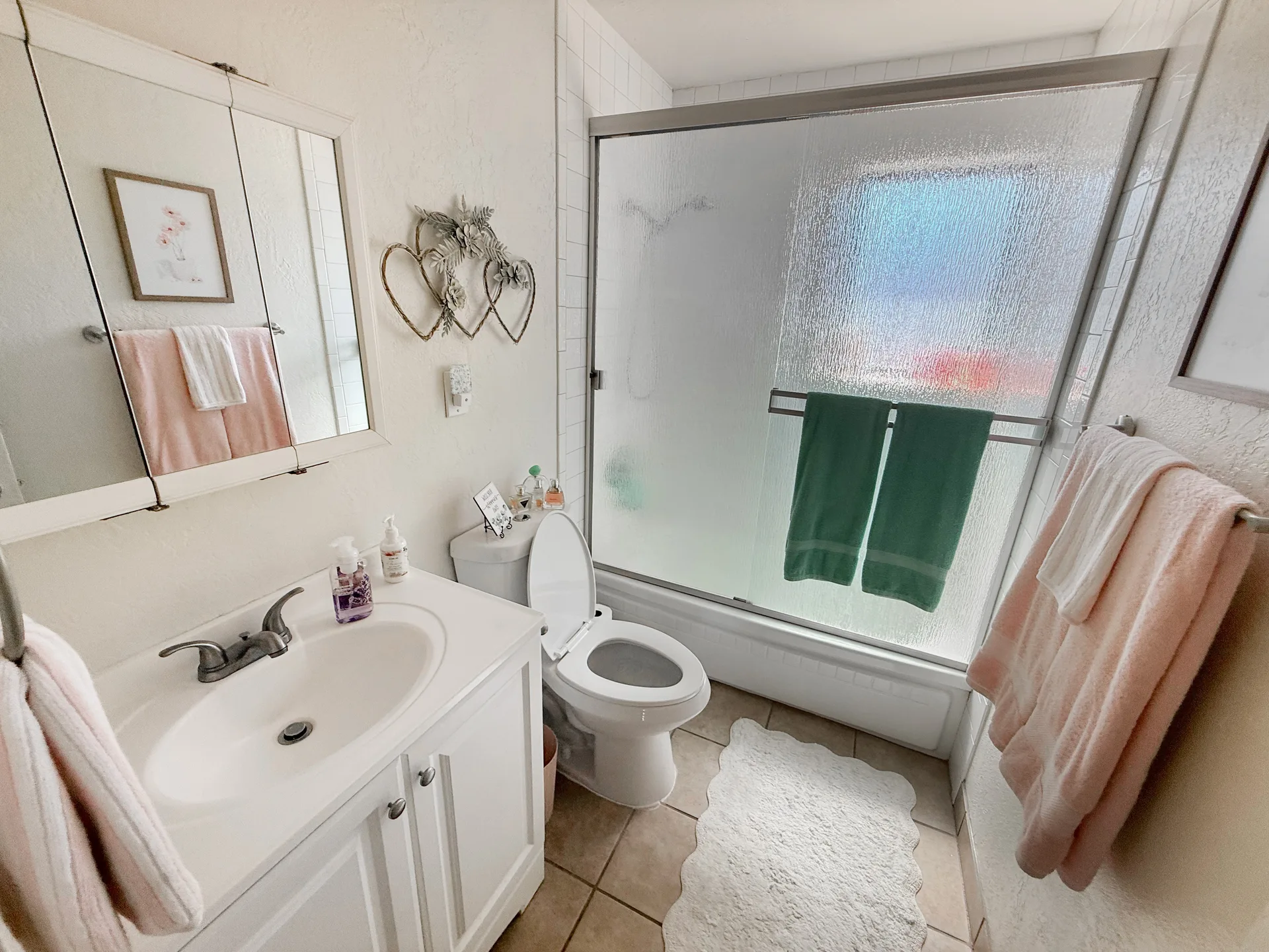 Bathroom with white vanity, chrome hardware, and sliding glass shower door