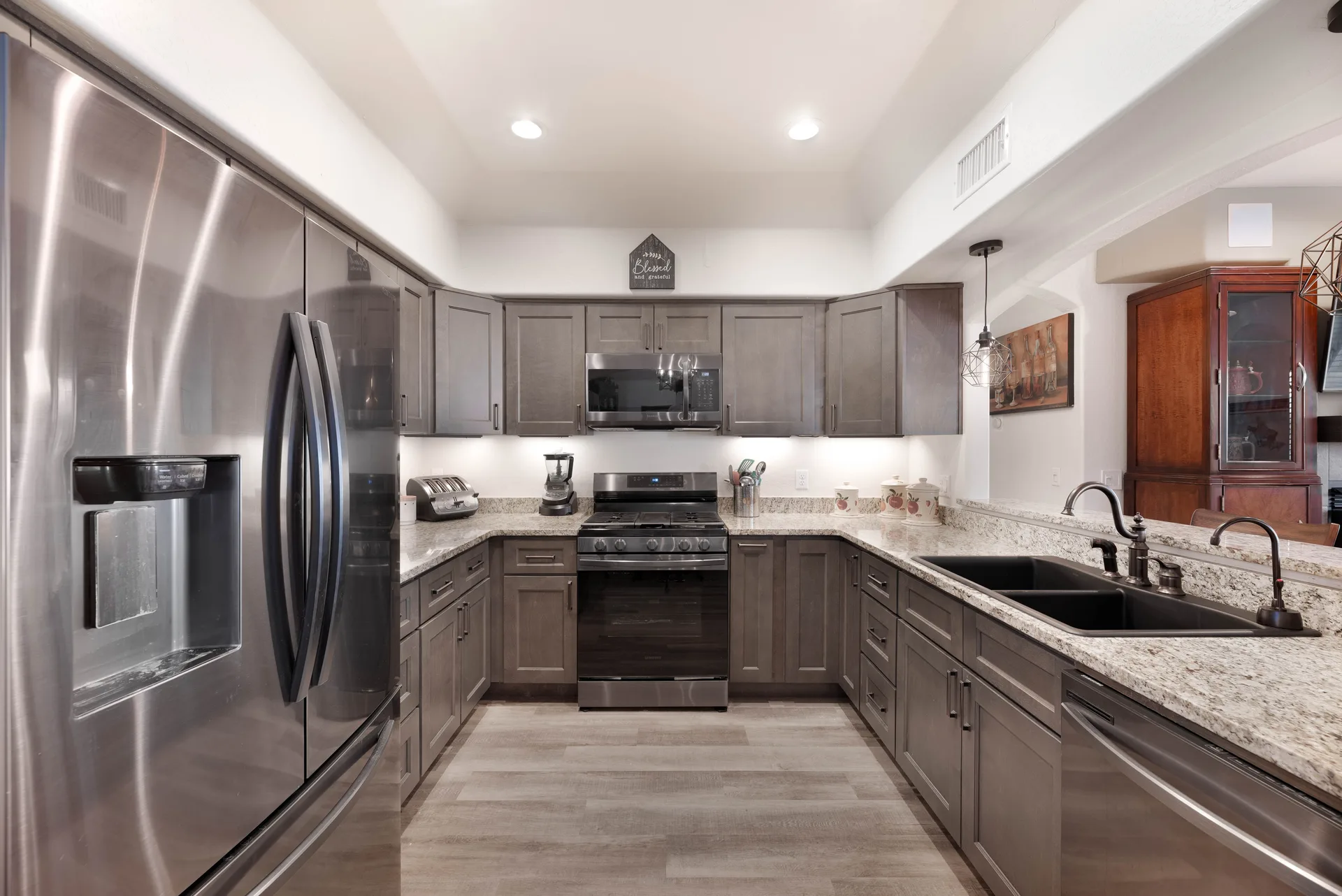 Renovated kitchen with grey shaker cabinets, granite countertops, and stainless steel appliances