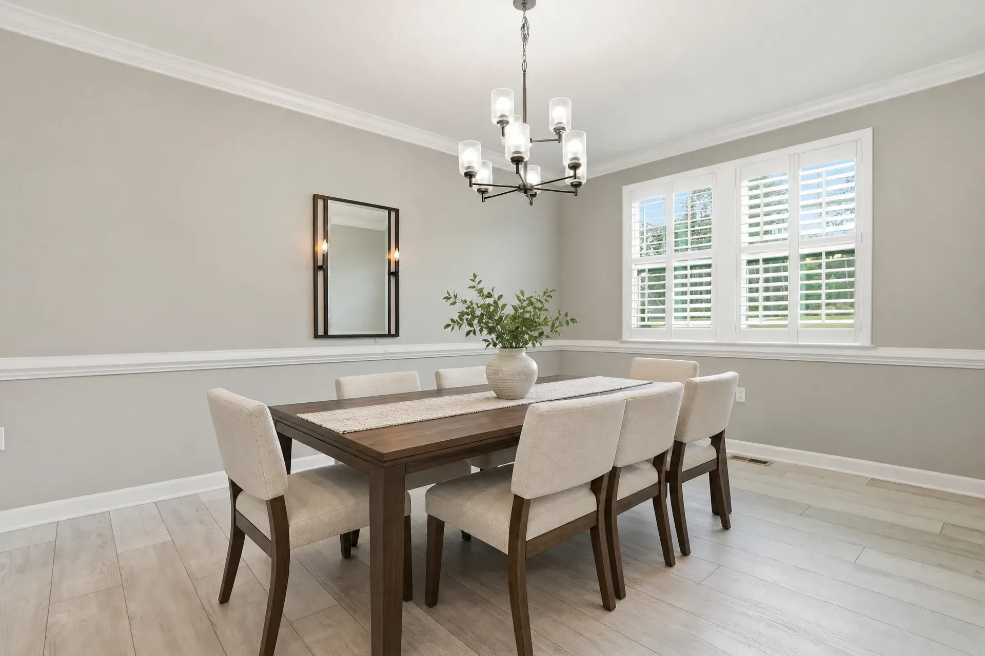 Formal dining room virtually staged with dining table, upholstered chairs, and modern chandelier