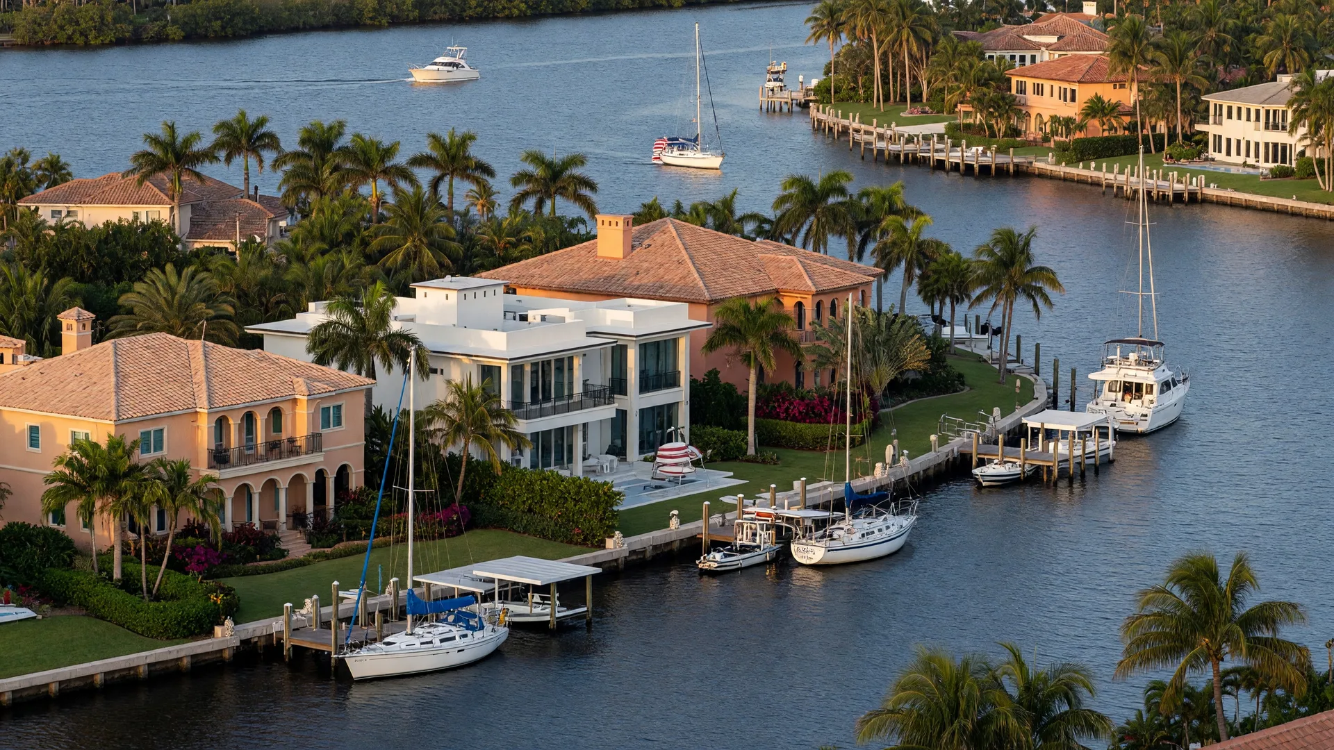 Waterfront homes in Spanish River Landings along the Intracoastal Waterway in Boca Raton, Florida with palm trees, private docks, and boats on a sunny afternoon
