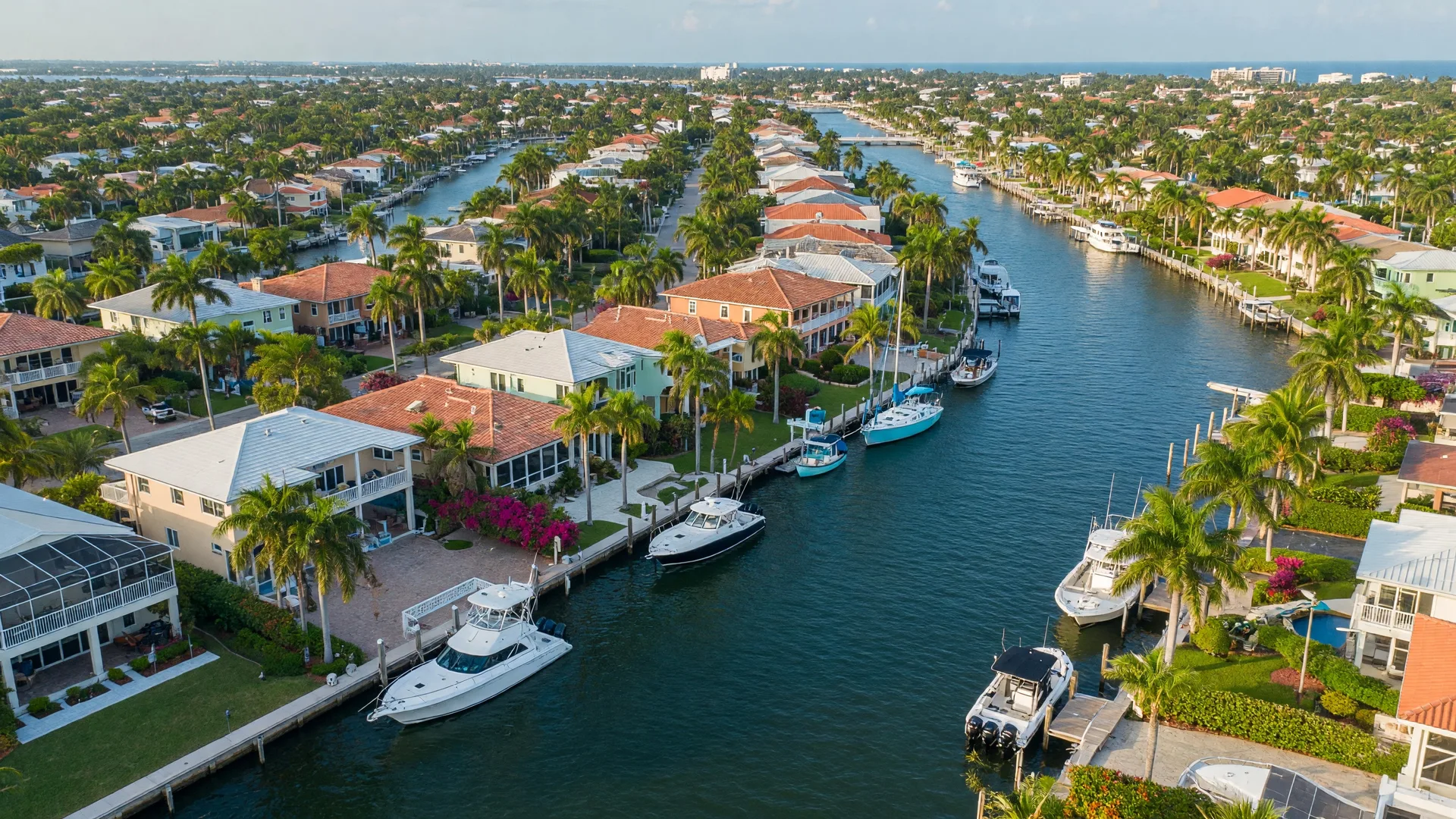 Waterfront homes along deep-water canals in Tropic Isle, Delray Beach, with private docks, palm trees, and blue skies