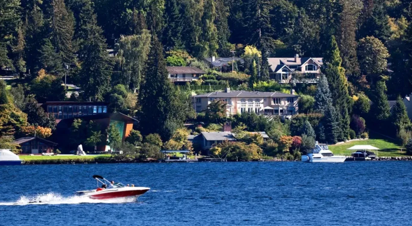 Waterfront aerial view looking toward Mercer Island shoreline with homes nestled among trees and boats on the water