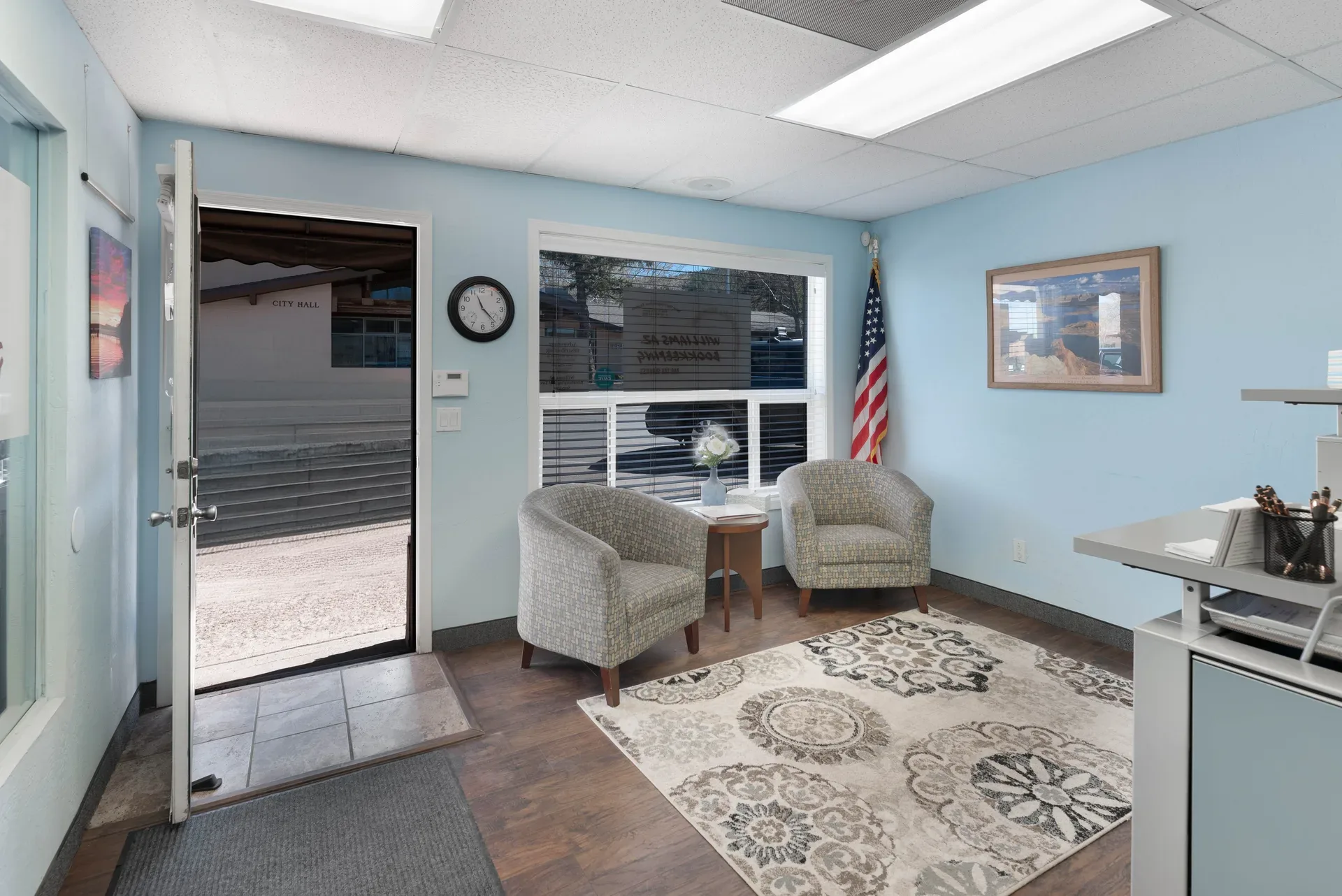 Commercial office lobby with upholstered seating, front desk, and drop ceiling