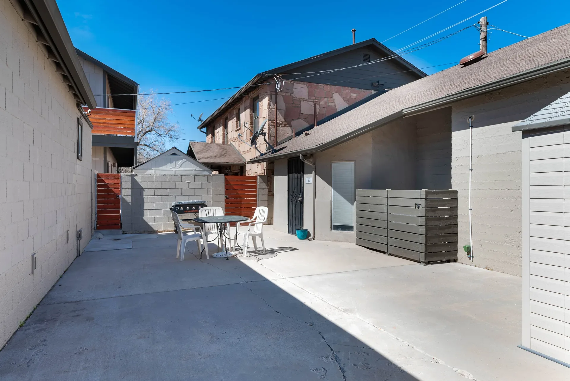 Private paved courtyard between buildings with concrete block walls and wood gates