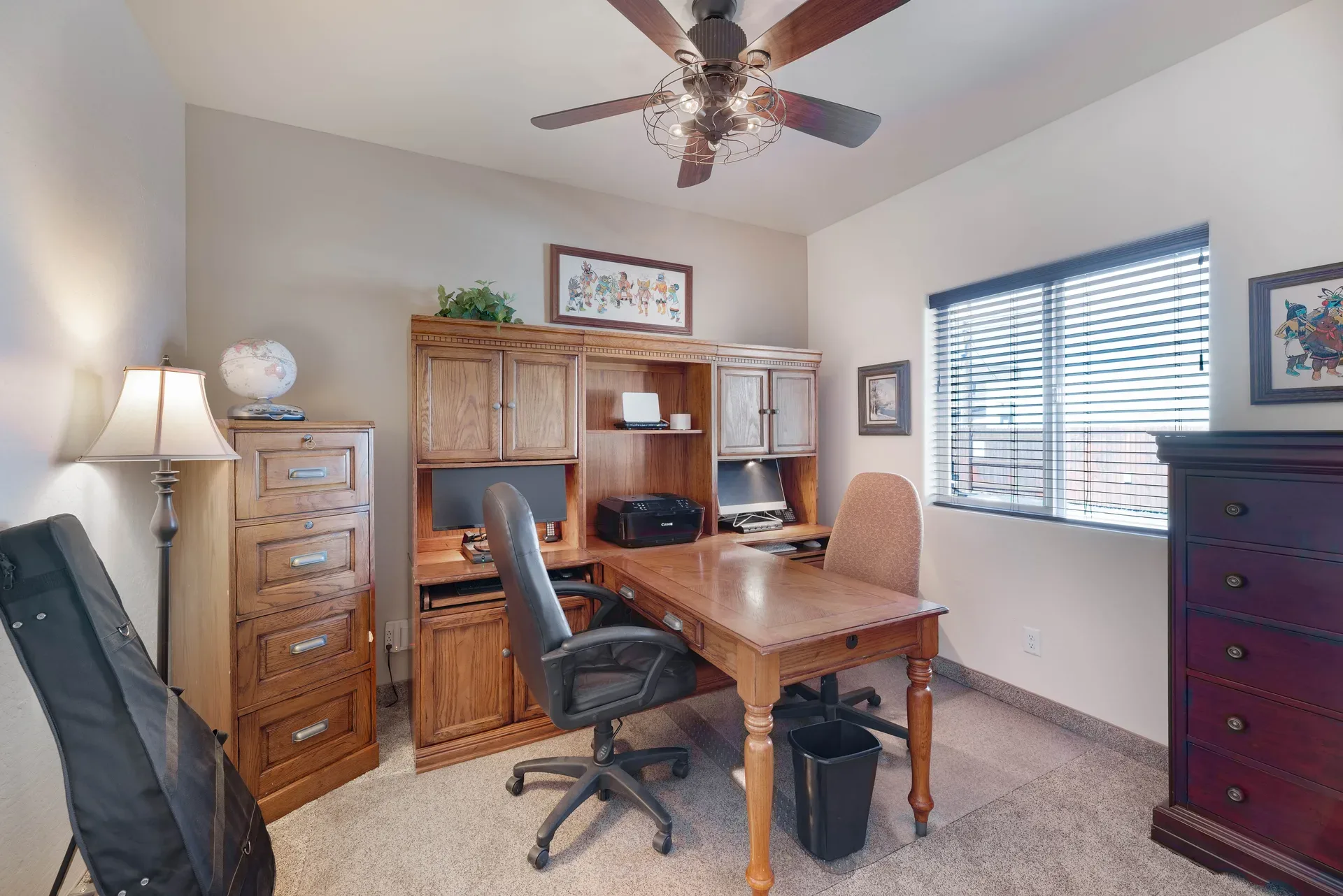 Vacant unit configured as a home office with carpeted floor and ceiling fan