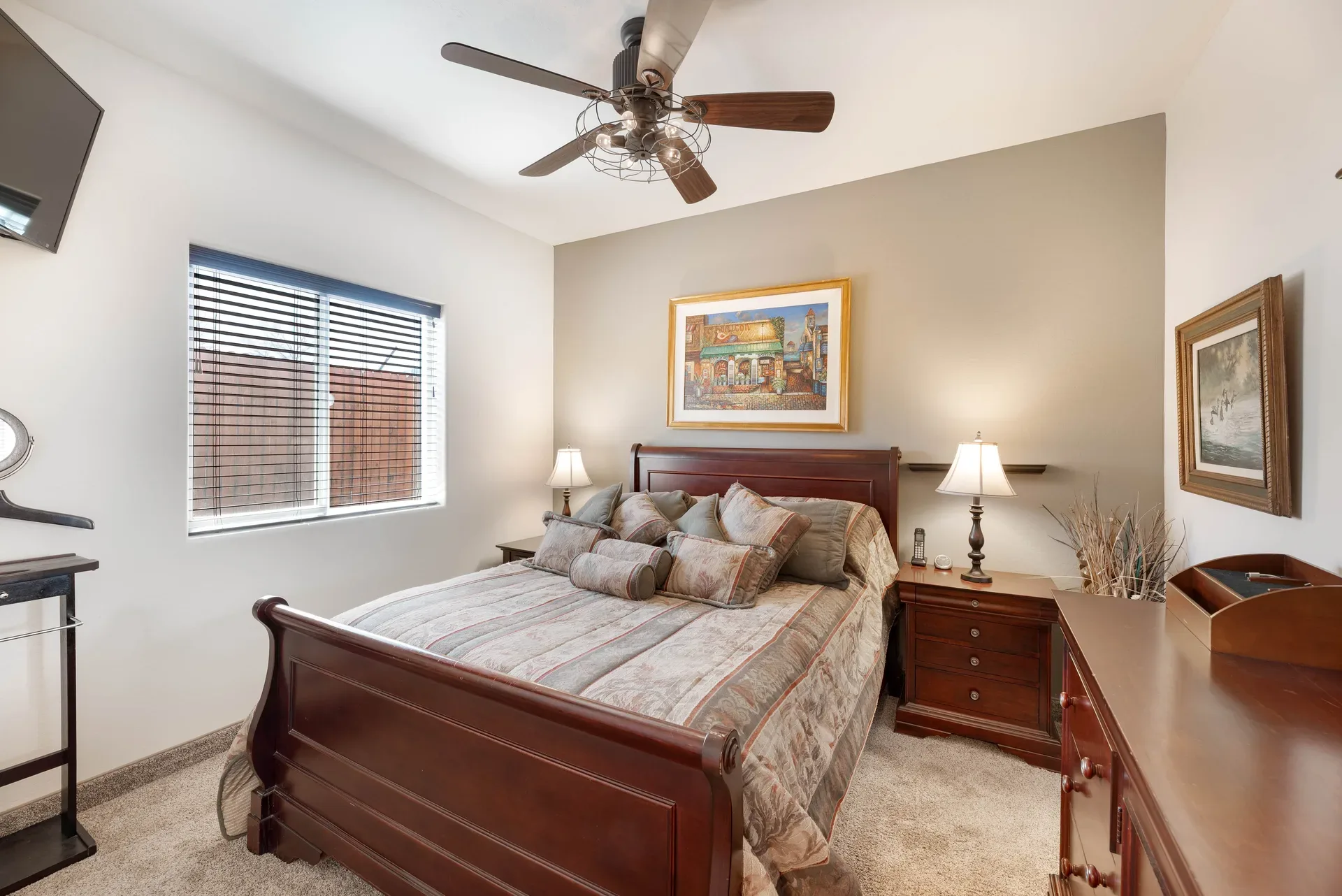 Furnished bedroom with dark wood sleigh bed, neutral carpeting, and window blinds