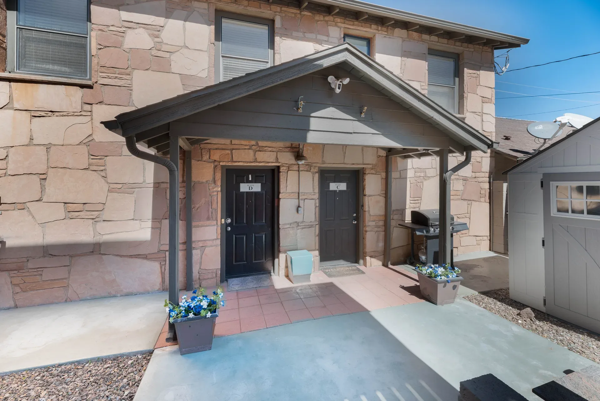 Building entry with flagstone veneer facade, covered porch, and numbered entry doors