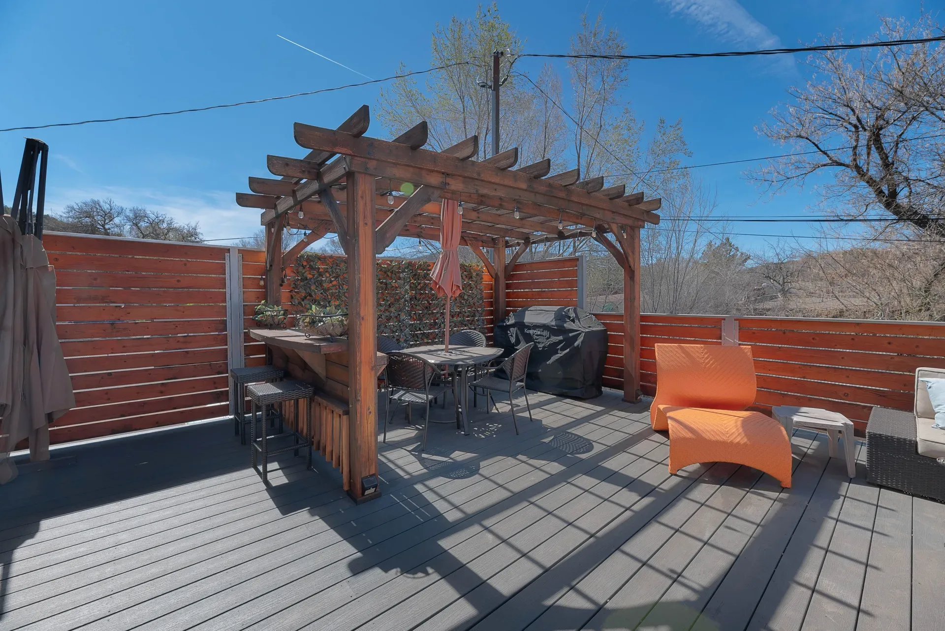 Outdoor courtyard with composite decking, wood slat fencing, and timber-frame pergola