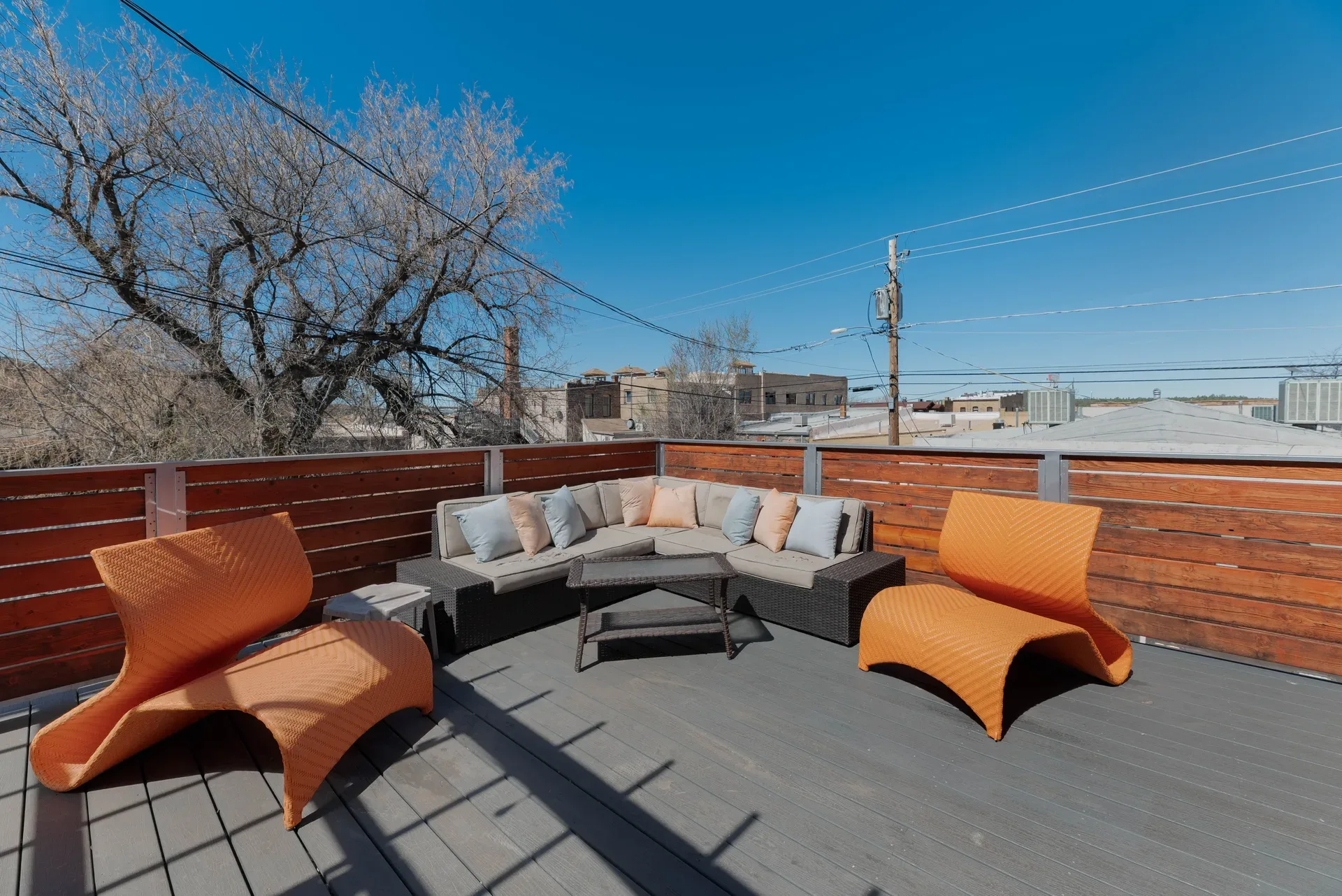 Rooftop deck with dark gray composite decking, cedar slat fencing, and modular furniture