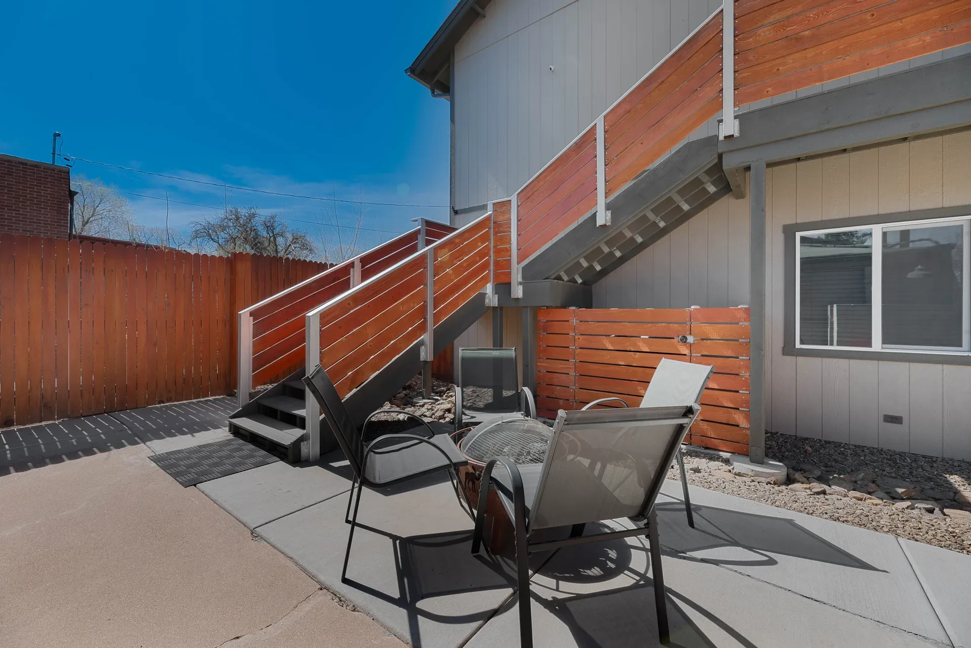 Courtyard scene with mixed materials including painted siding, wood fencing, and metal stairwell