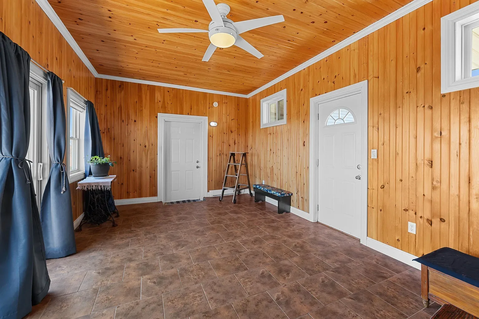 Sunroom with wood paneling and tile flooring