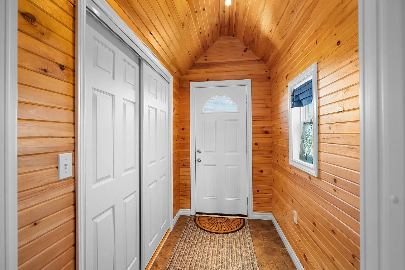 Wood-paneled foyer with vaulted ceiling