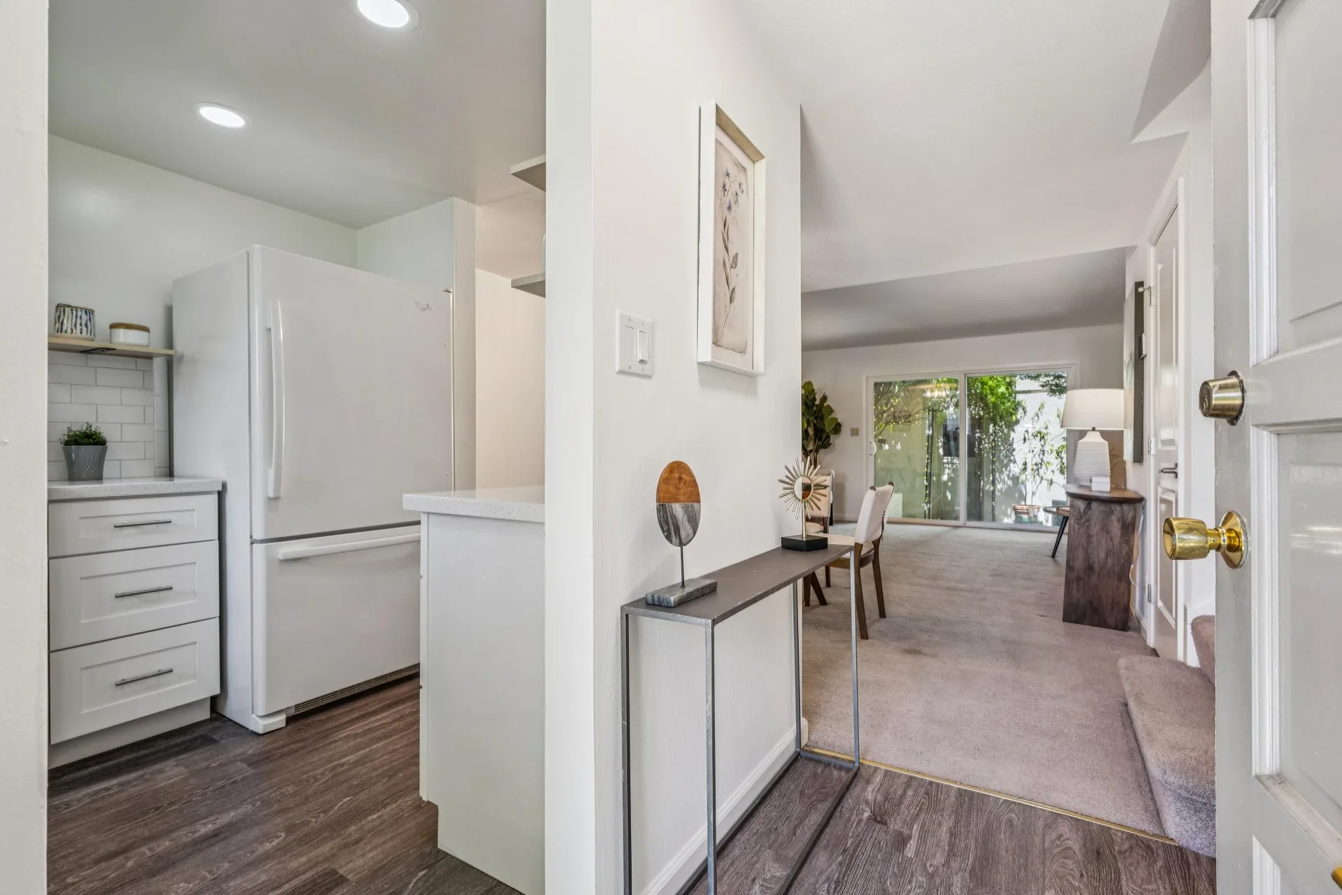 First-person view from open front door looking into the home with vinyl plank entry and carpeted living area