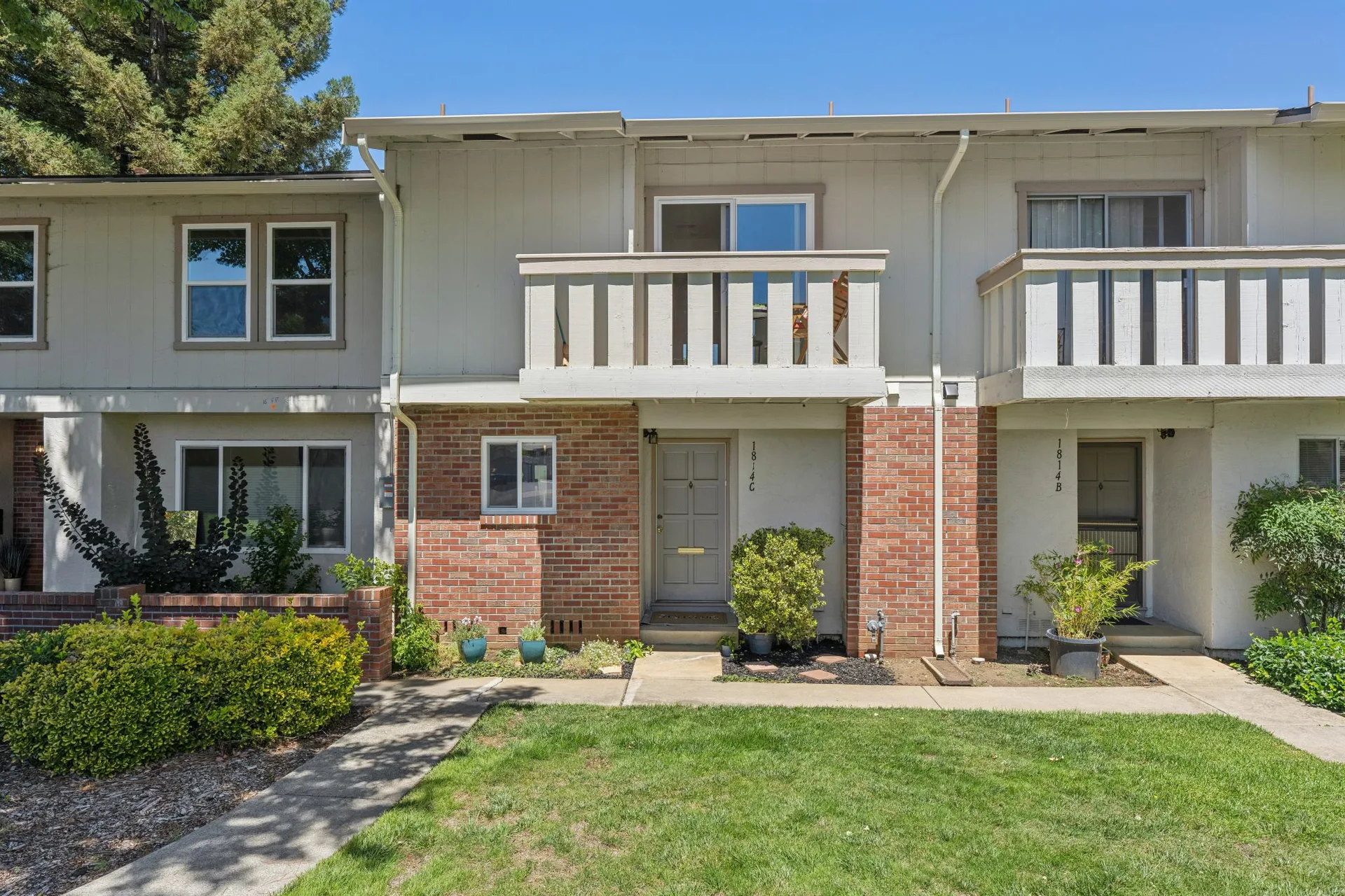 Close-up of two-story townhome facade with balcony and brick accents