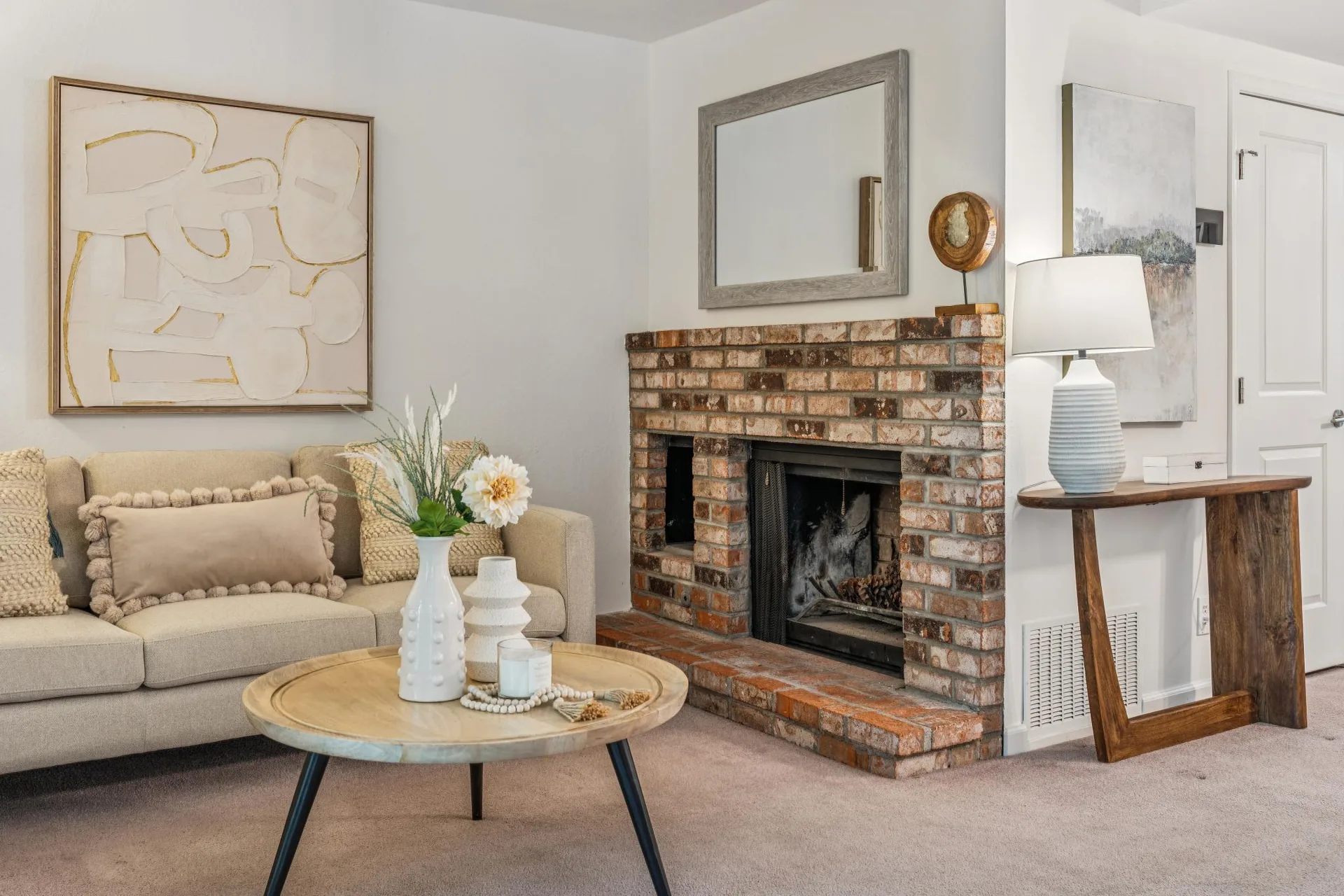 Living room with brick fireplace hearth, throw pillows, and wall art