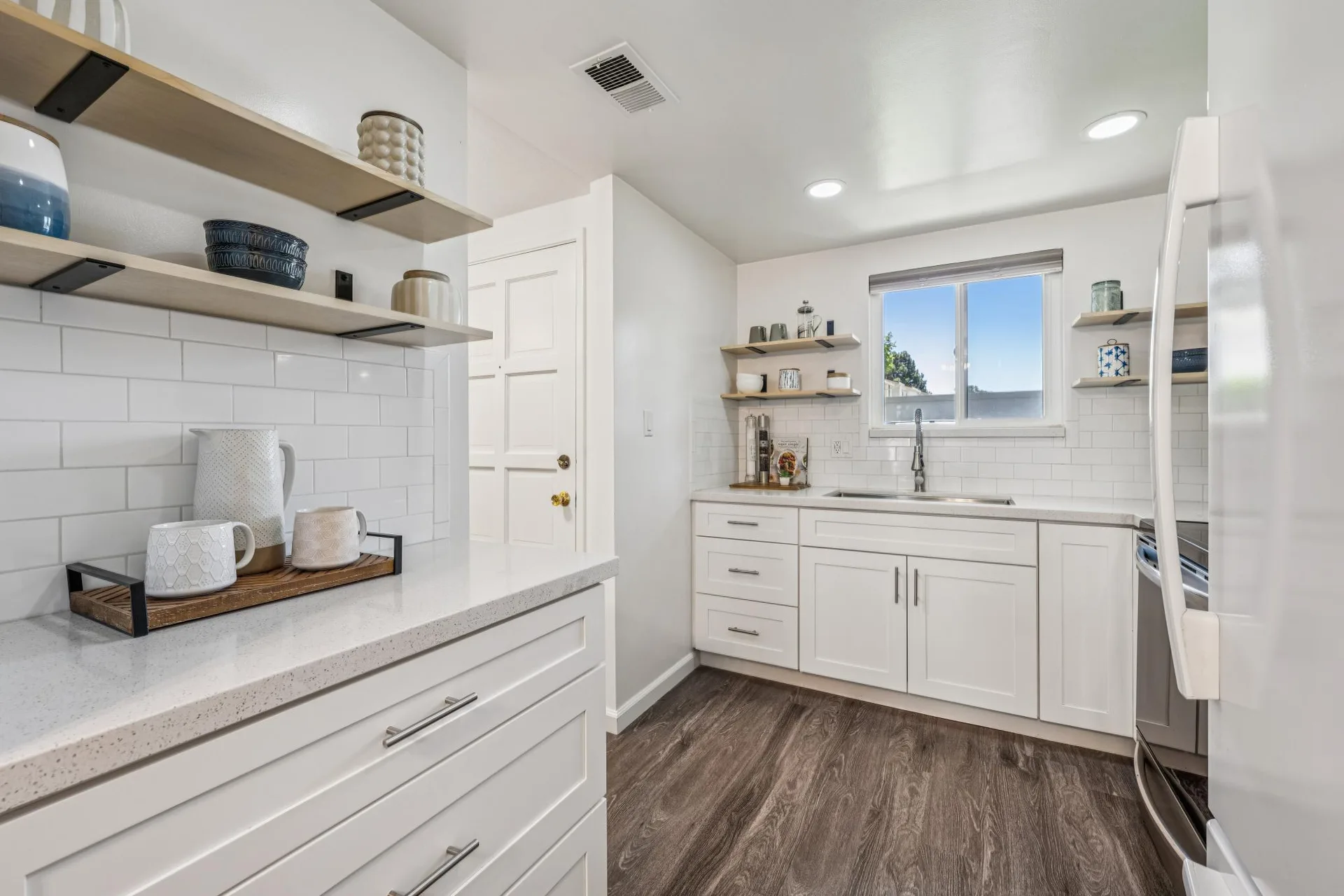 Updated kitchen with white shaker cabinets, subway tile, and open wood shelving