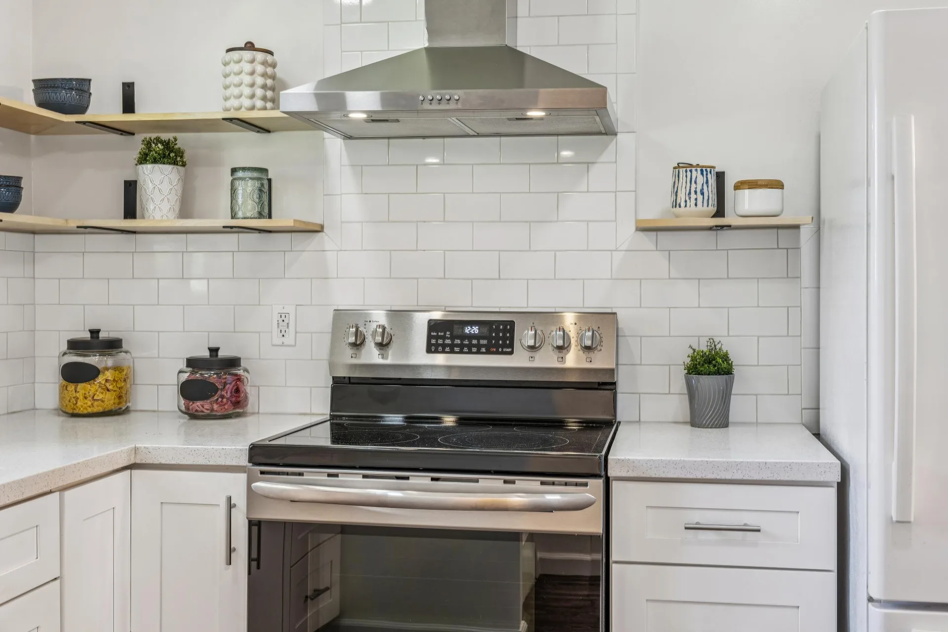 Kitchen stove range with white subway tile and open wood shelving above