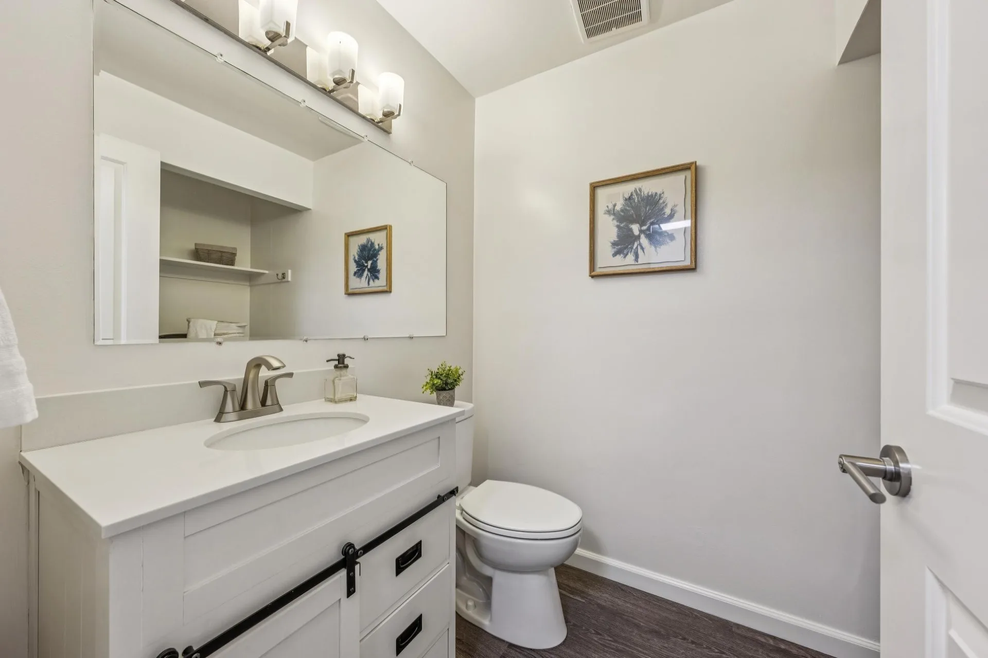 Powder room with white vanity, barn-door style hardware, and grey wood-look flooring