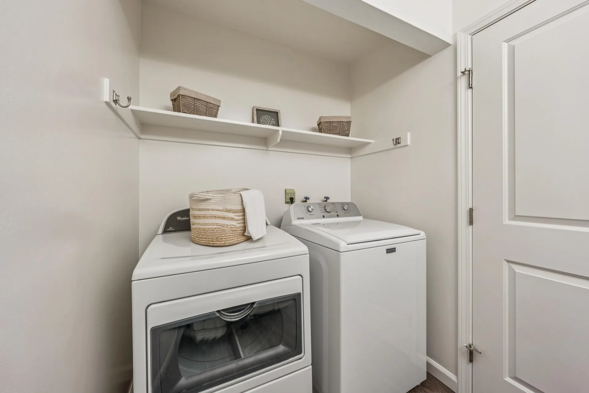 Dedicated laundry closet with washer, dryer, and overhead shelving