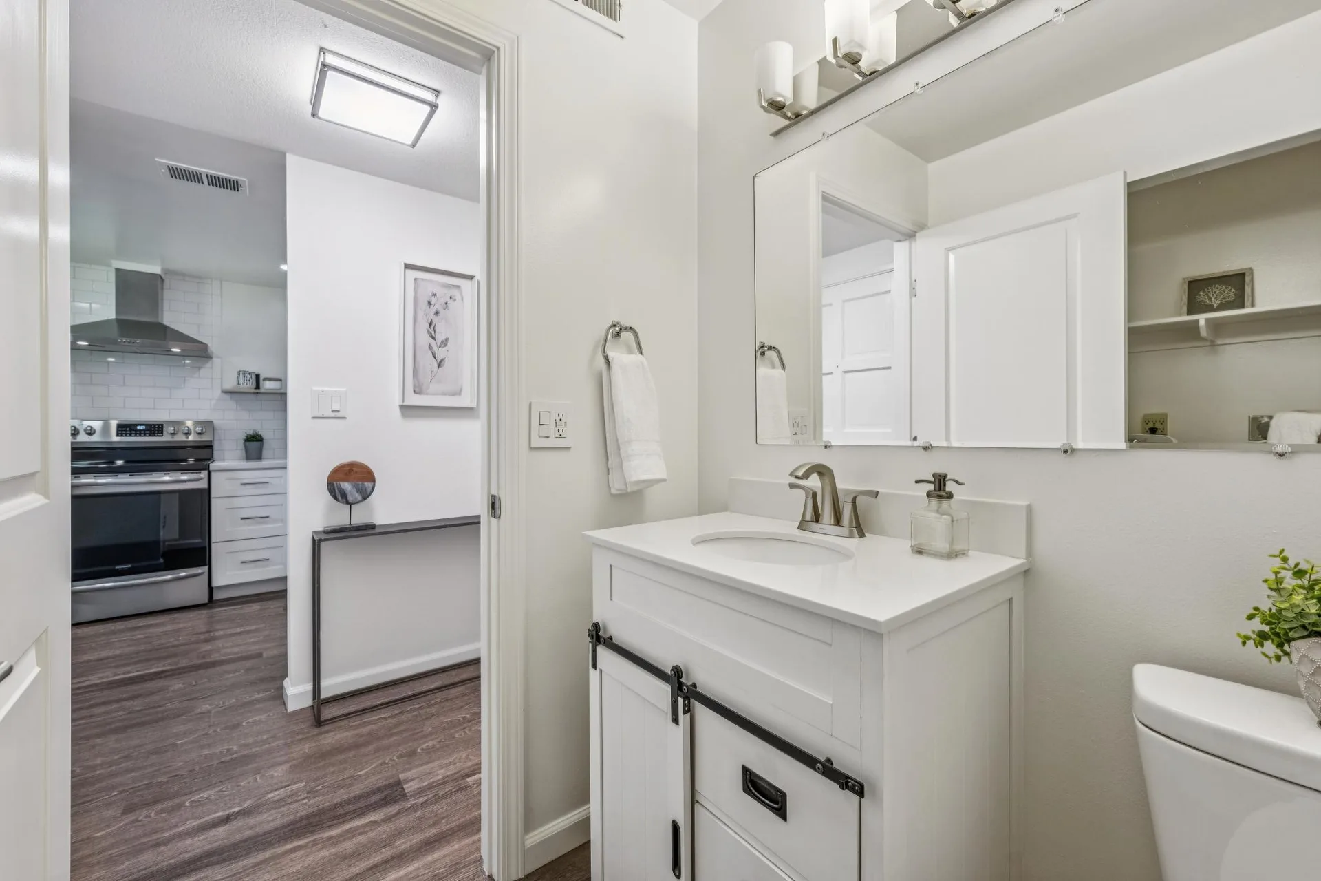Powder room looking into the kitchen with white vanity and brushed nickel faucet