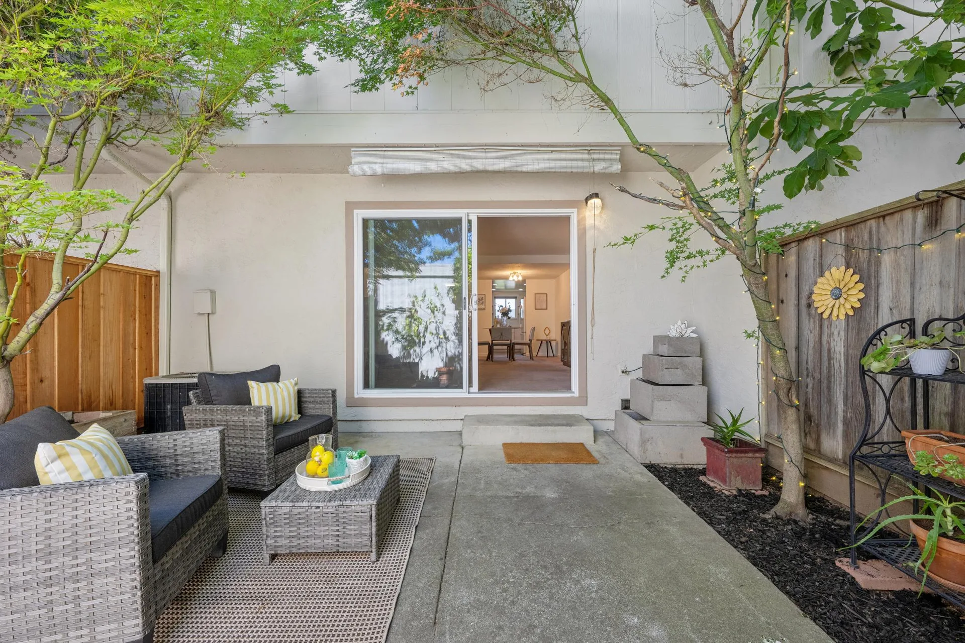 Backyard patio with wicker chairs, floral rug, bamboo shade, and stone fountain