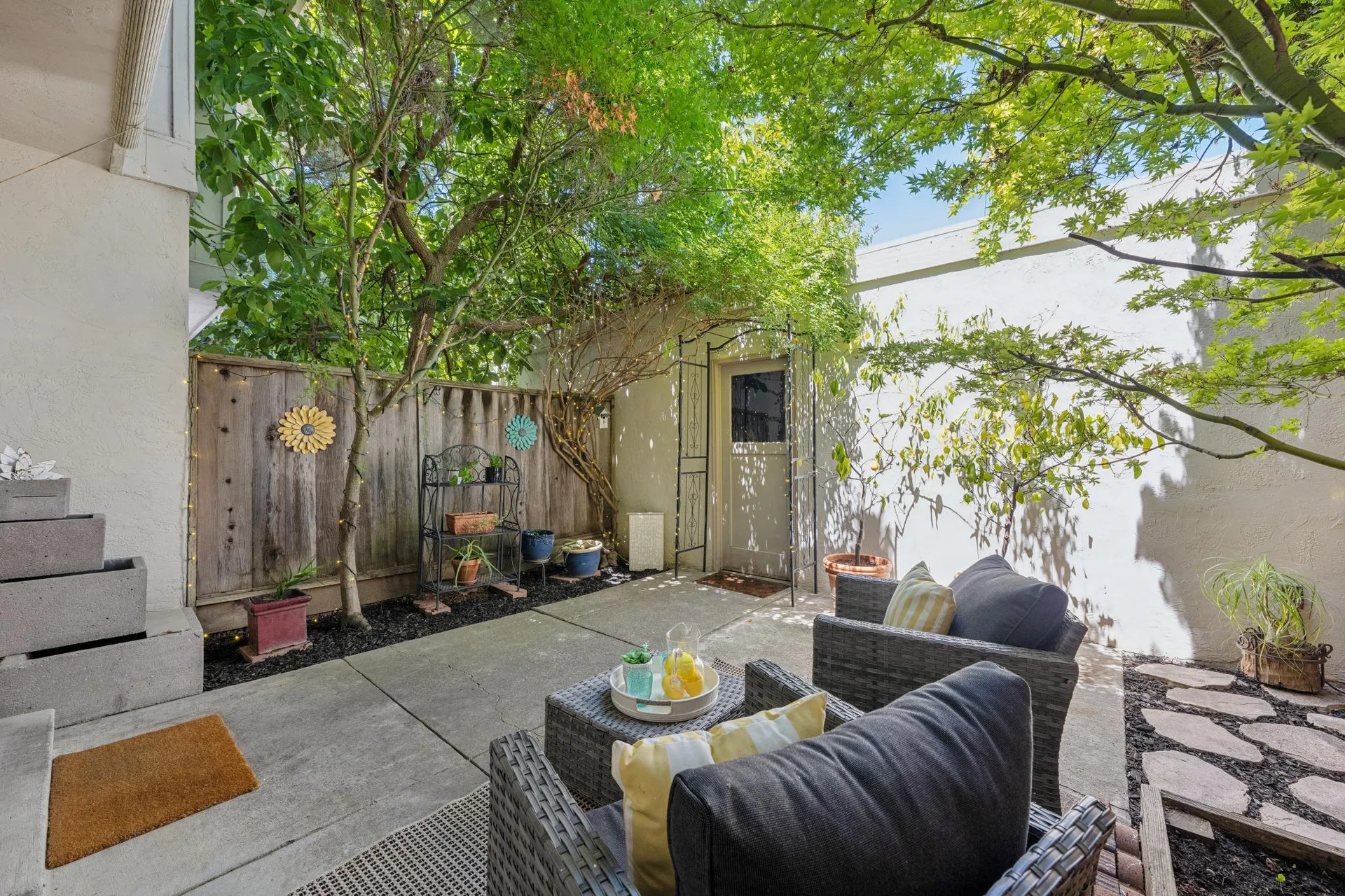 Backyard patio with woven armchairs, ottomans, and decorative wall hangings