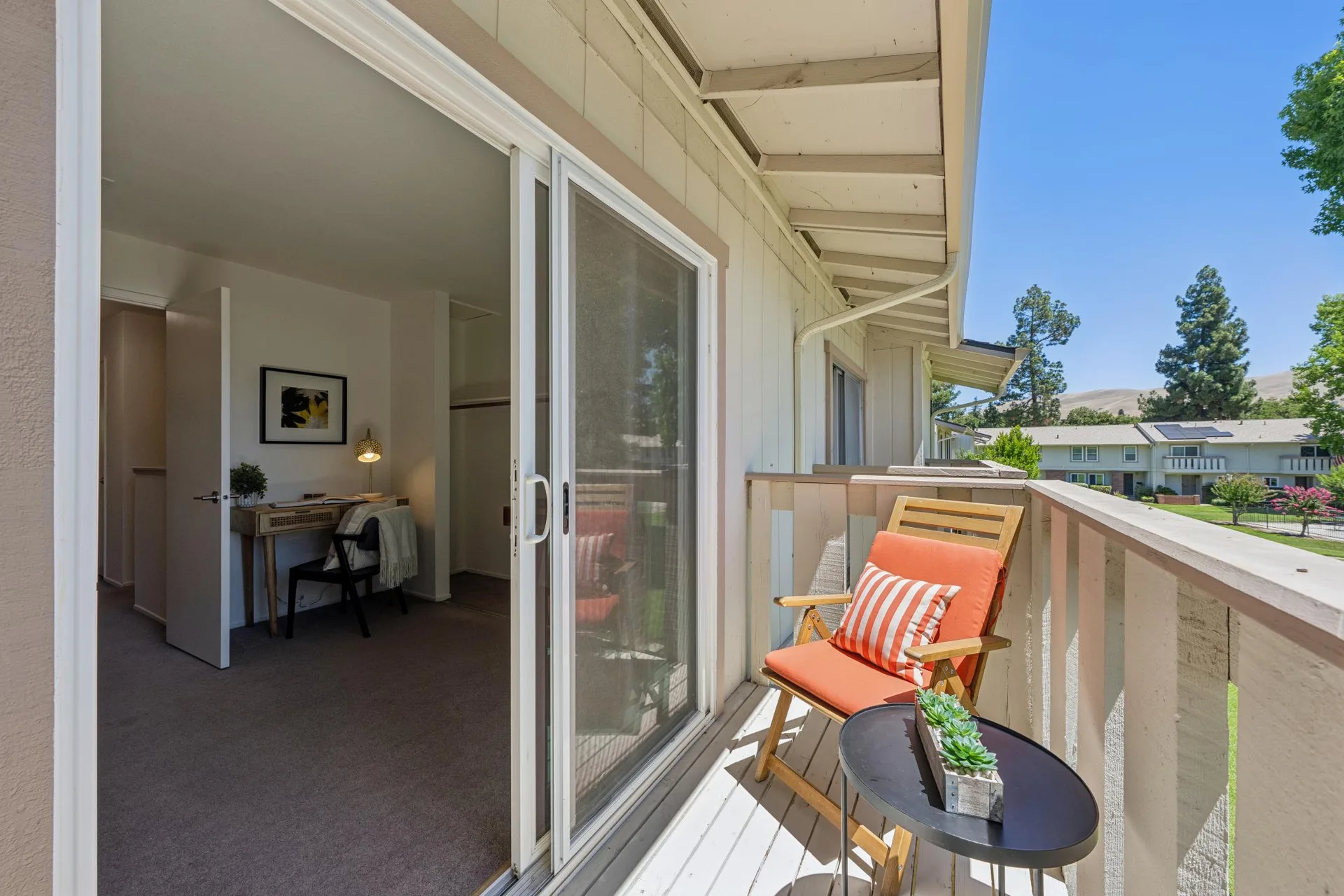 Second-story balcony with wooden railing and sliding glass door to bedroom